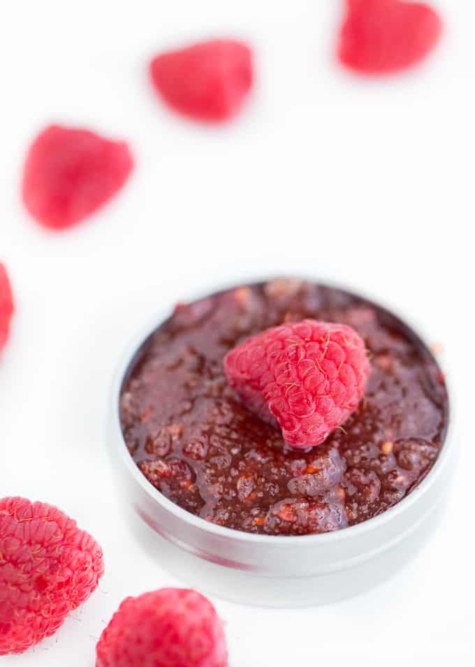 Jar of rasperry lip scrub on white background with fresh rasperries