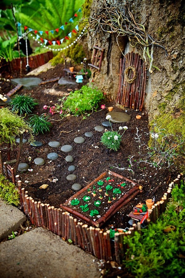 Natural looking fairy garden with rock path, small greenery, and wooden stick made door