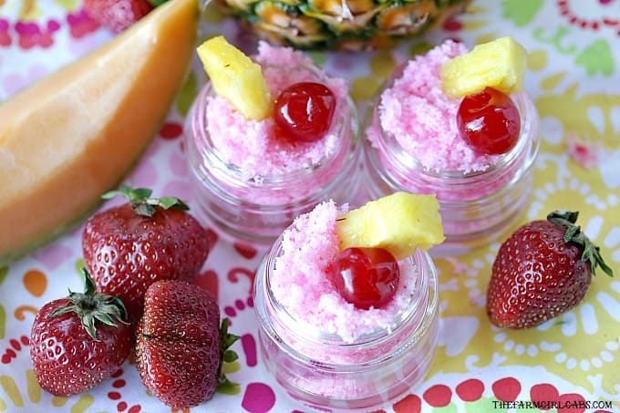 Three small jars of pink tropical punch lip scrub with strawberries, pineapple wedge, and cherries on top