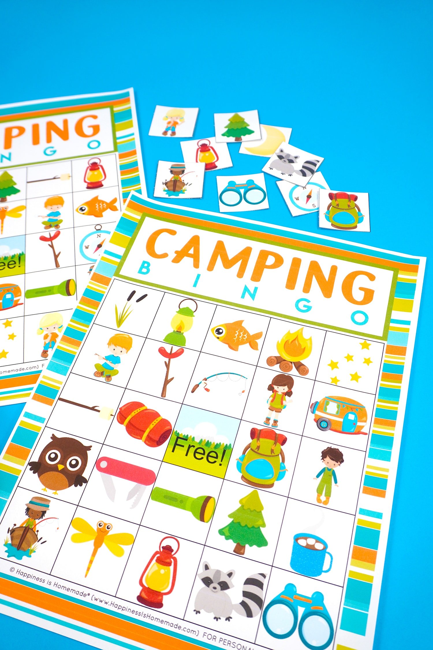 Two Camping Bingo Printable game cards on a blue background with scattered calling cards
