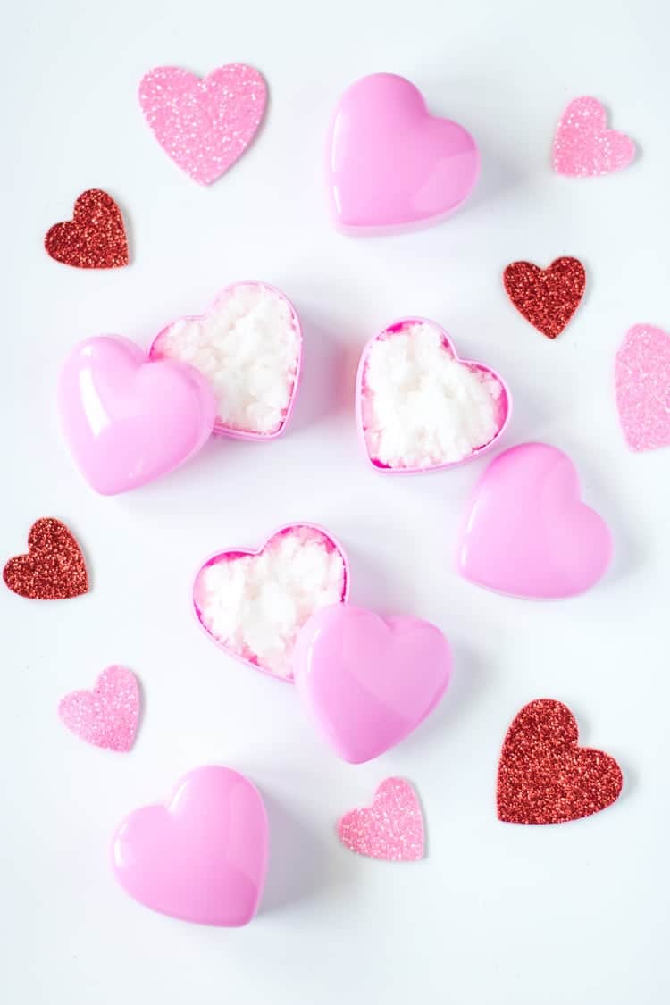 Heart jars of sugar lip scrub on a white background with glittery red hearts