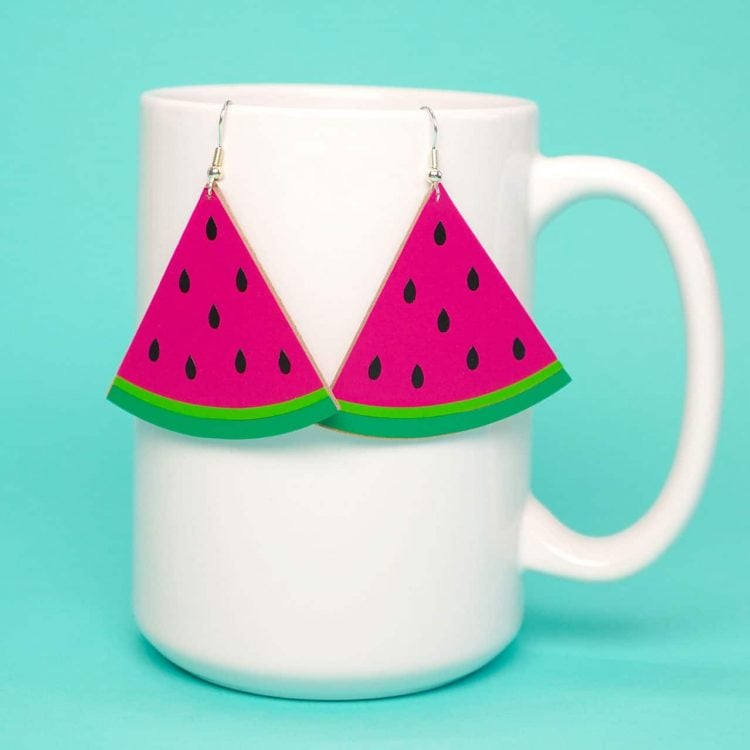 cute watermelon slice earrings hanging on white mug