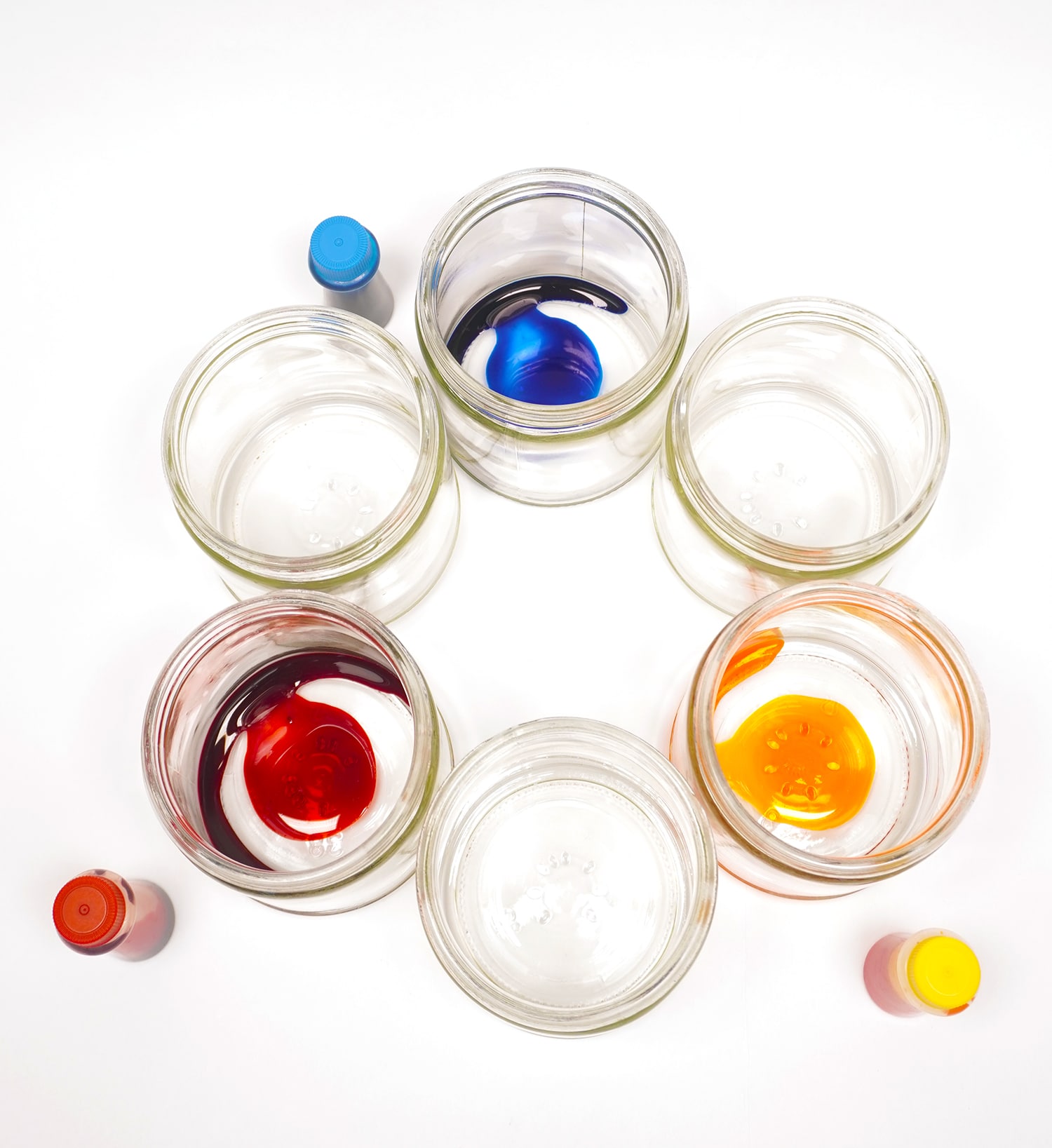 drops of red, yellow, and blue food coloring in 3 out of 6 jars placed in a circle