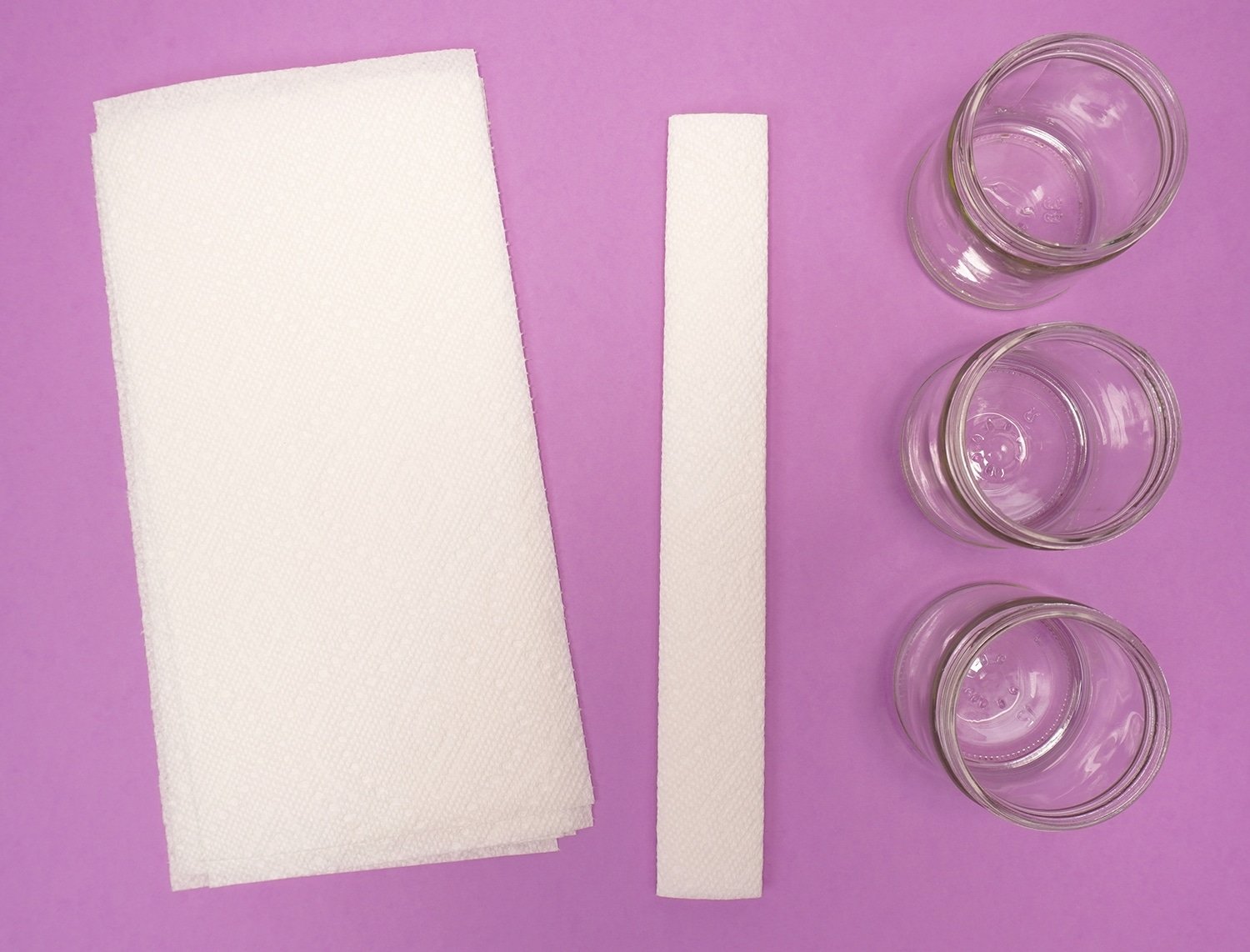 strips of white paper, paper towels and clear jars laid out on table