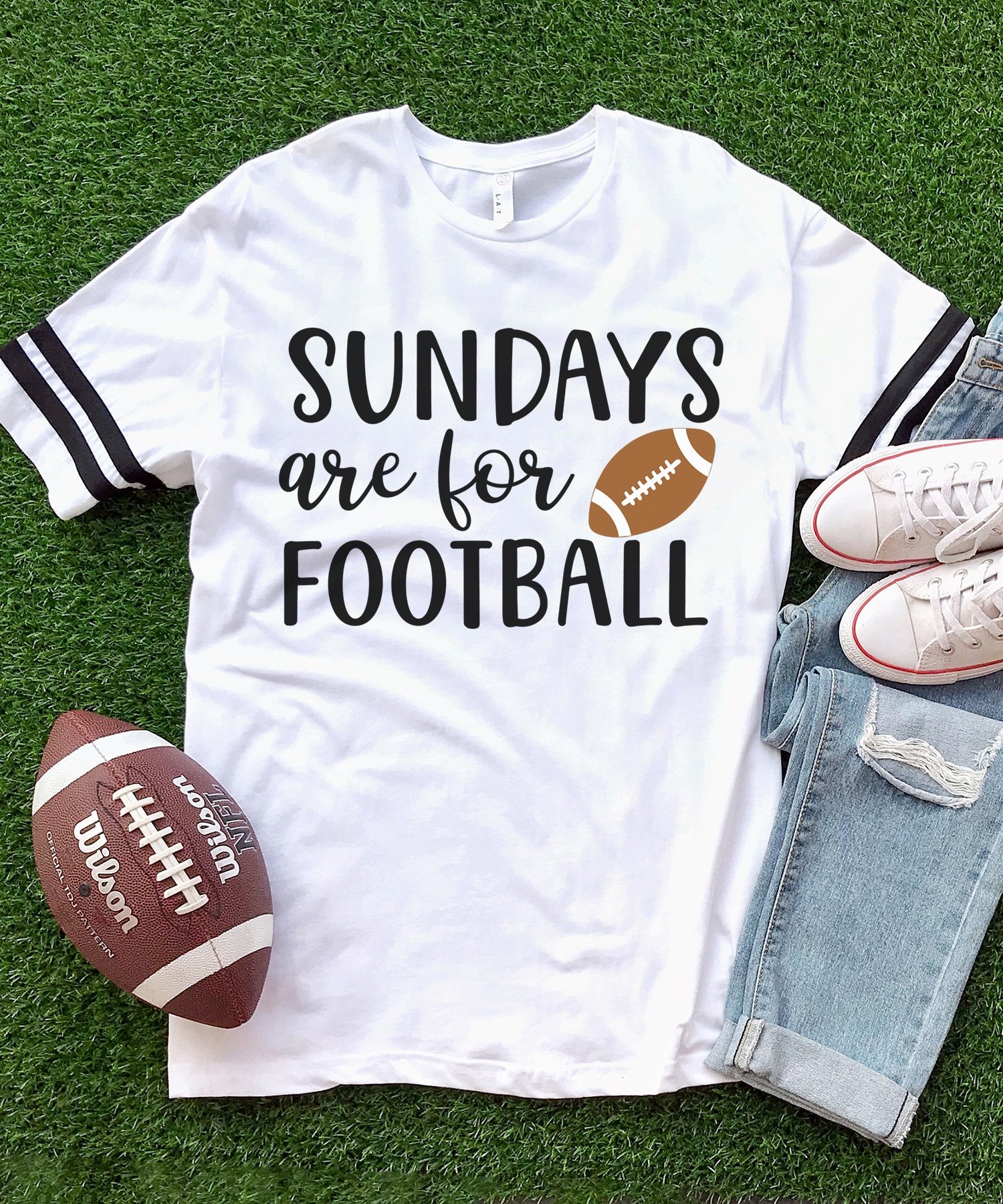 White shirt with "Sundays are for Football" graphic on a grass turf background with jeans, shoes, and a football