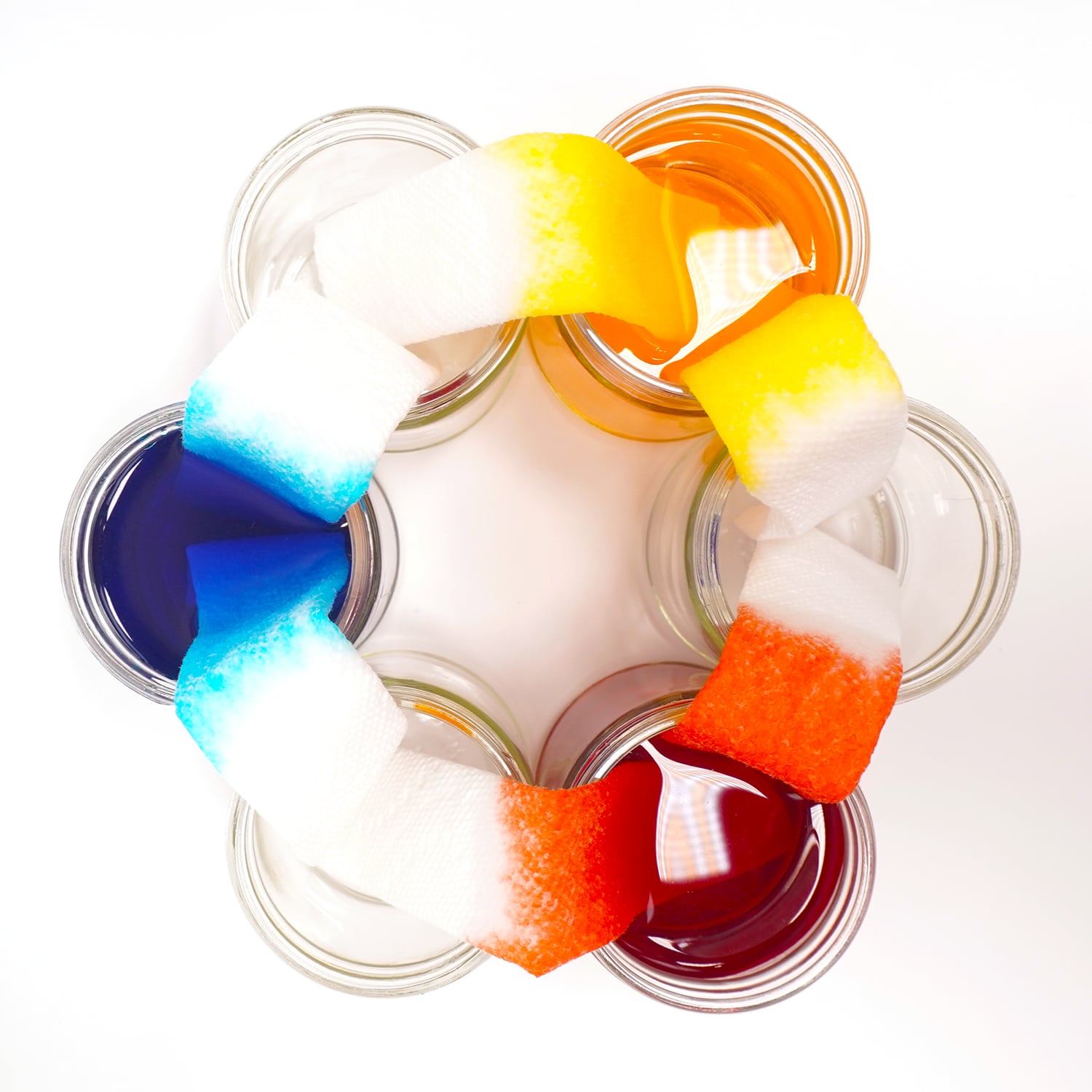 overhead of colors bleeding onto the strips of paper from colored jars