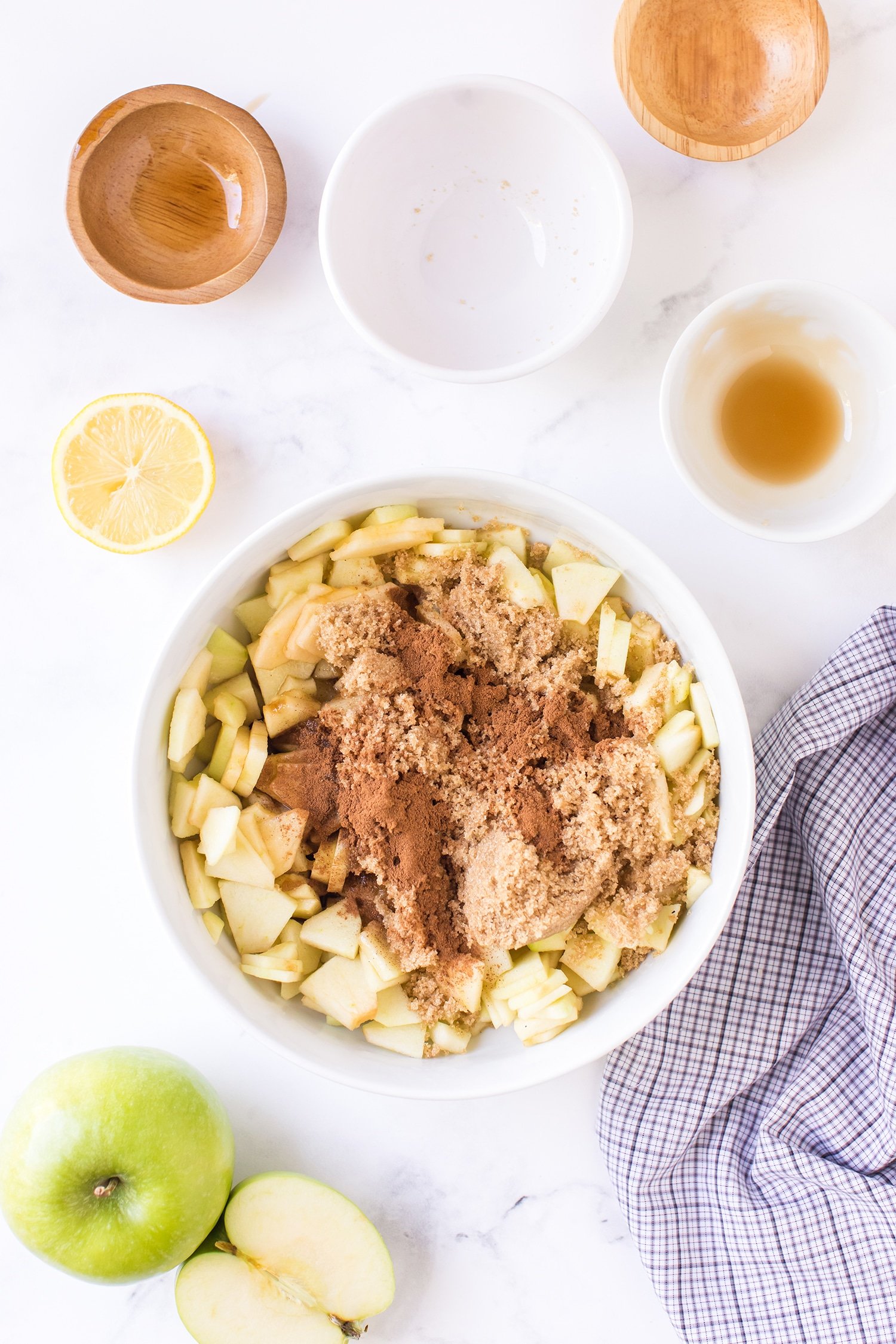 Apples , cinnamon, and brown sugar in bowl surrounded by apples and empty smaller bowls