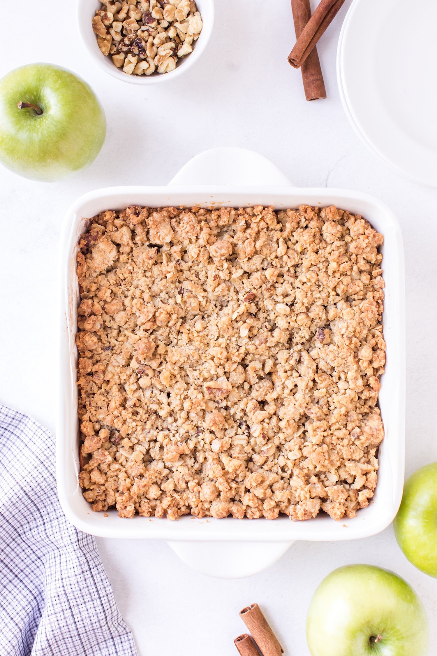 Apple pie bars with streusel topping in white backing dish with green apple on the side