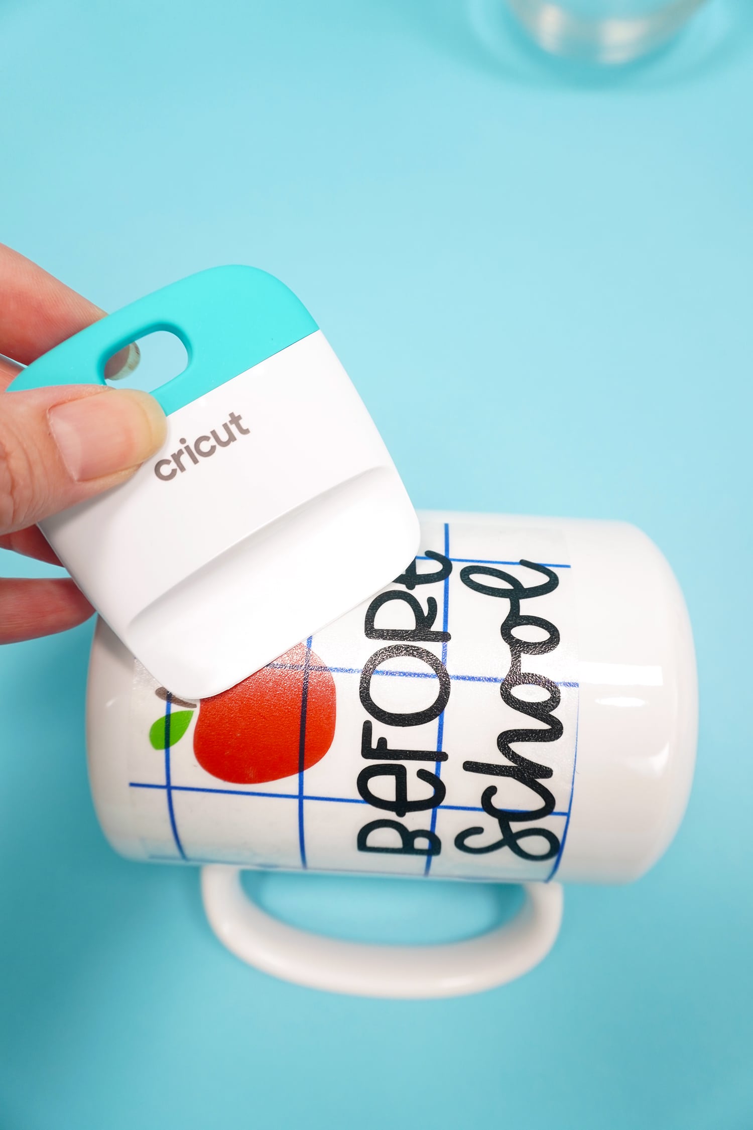 Using a scraping tool to apply an apple and "before school" design to a white mug