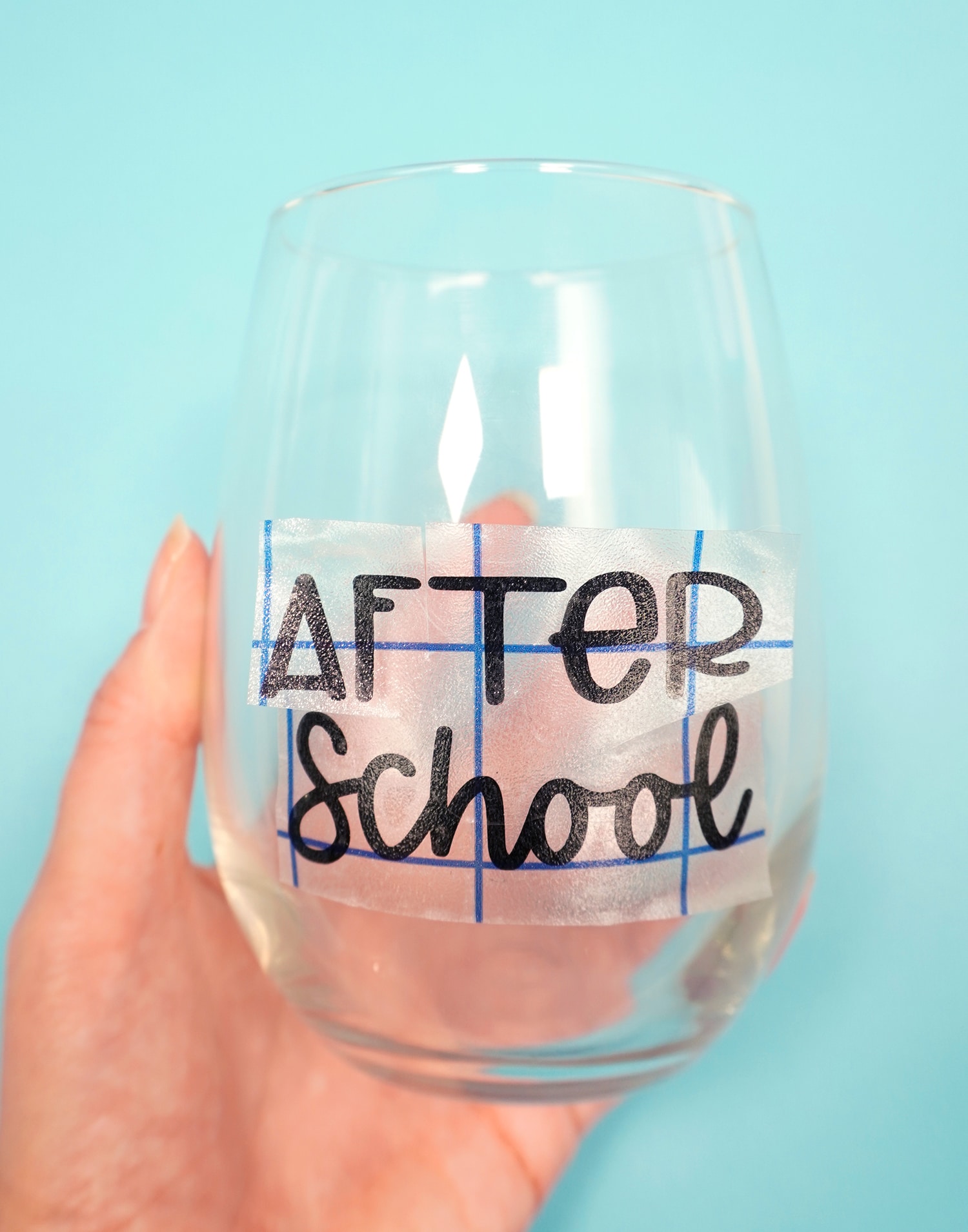 Hand holding stemless wine glass with "After School" vinyl transfer