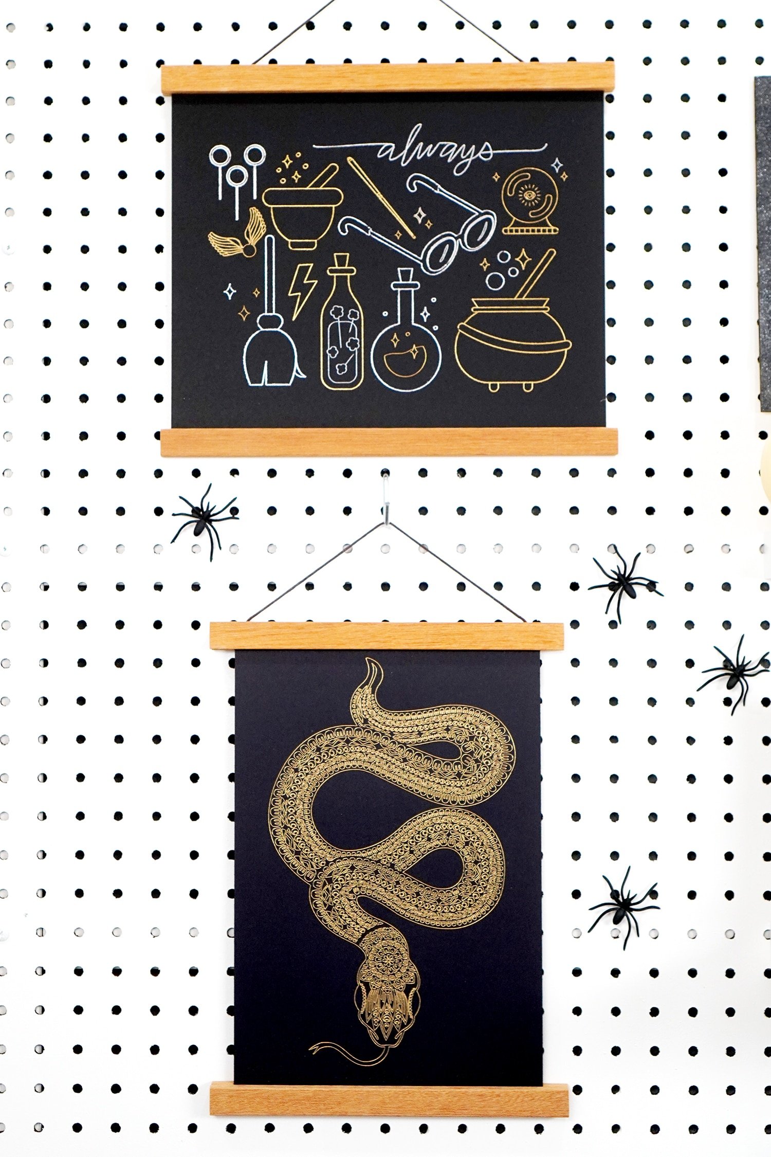 Halloween foil art prints (snake and wizard) hanging on pegboard with spiders