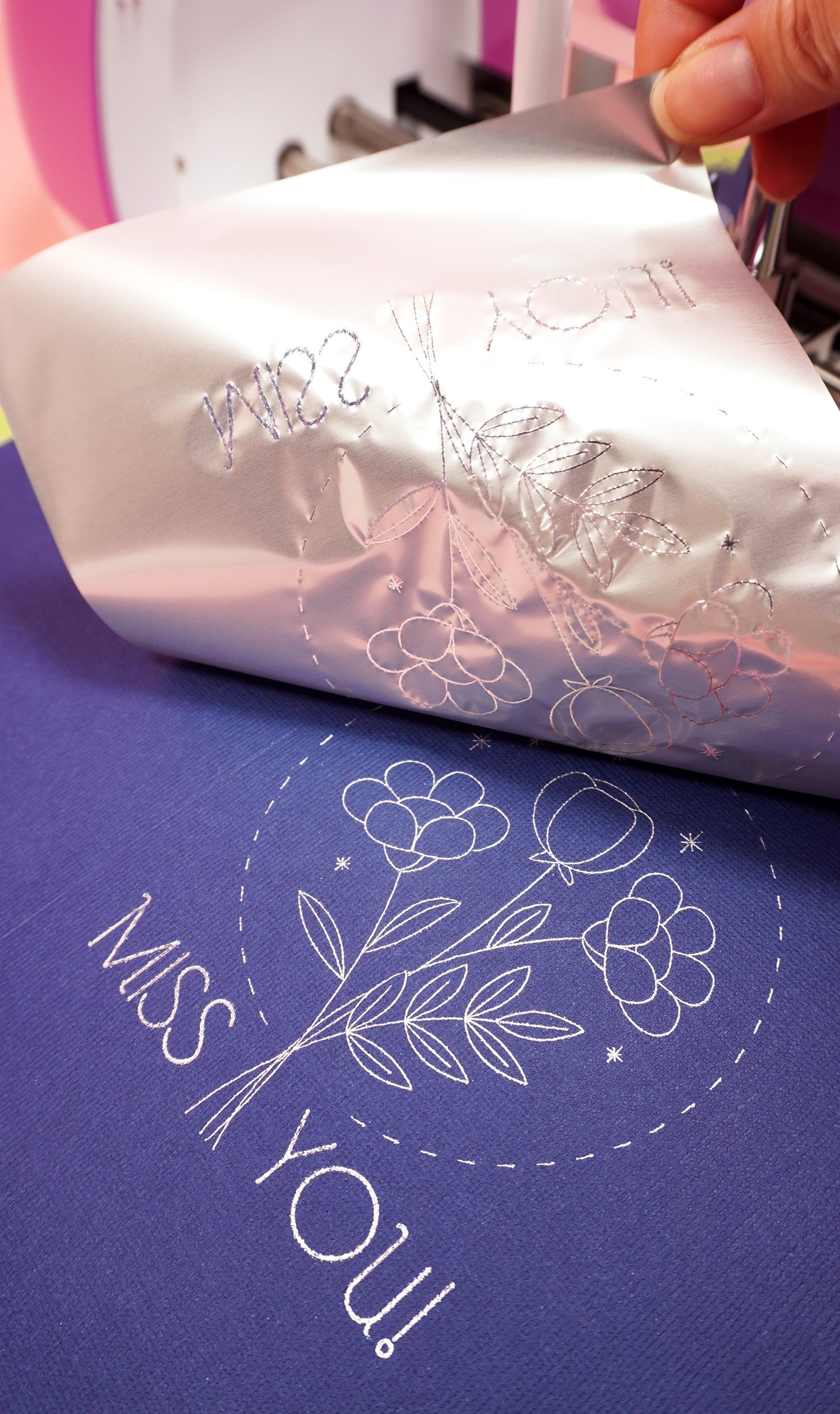 Peeling back silver foil sheet to reveal "Miss You" and flower bouquet foil design on navy blue card