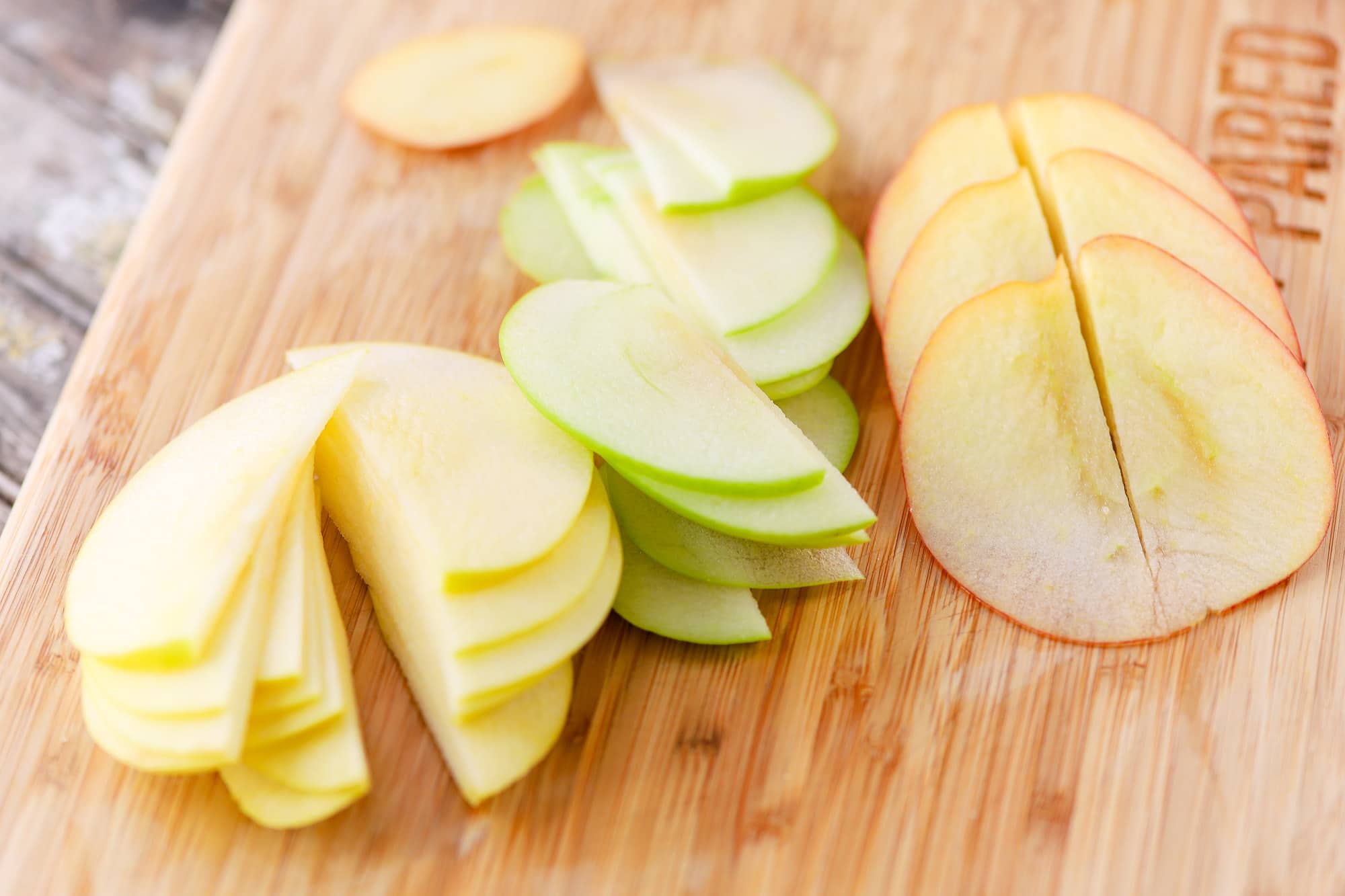 Red, Yellow, and Green Apple Slices on a Wood Cutting Board