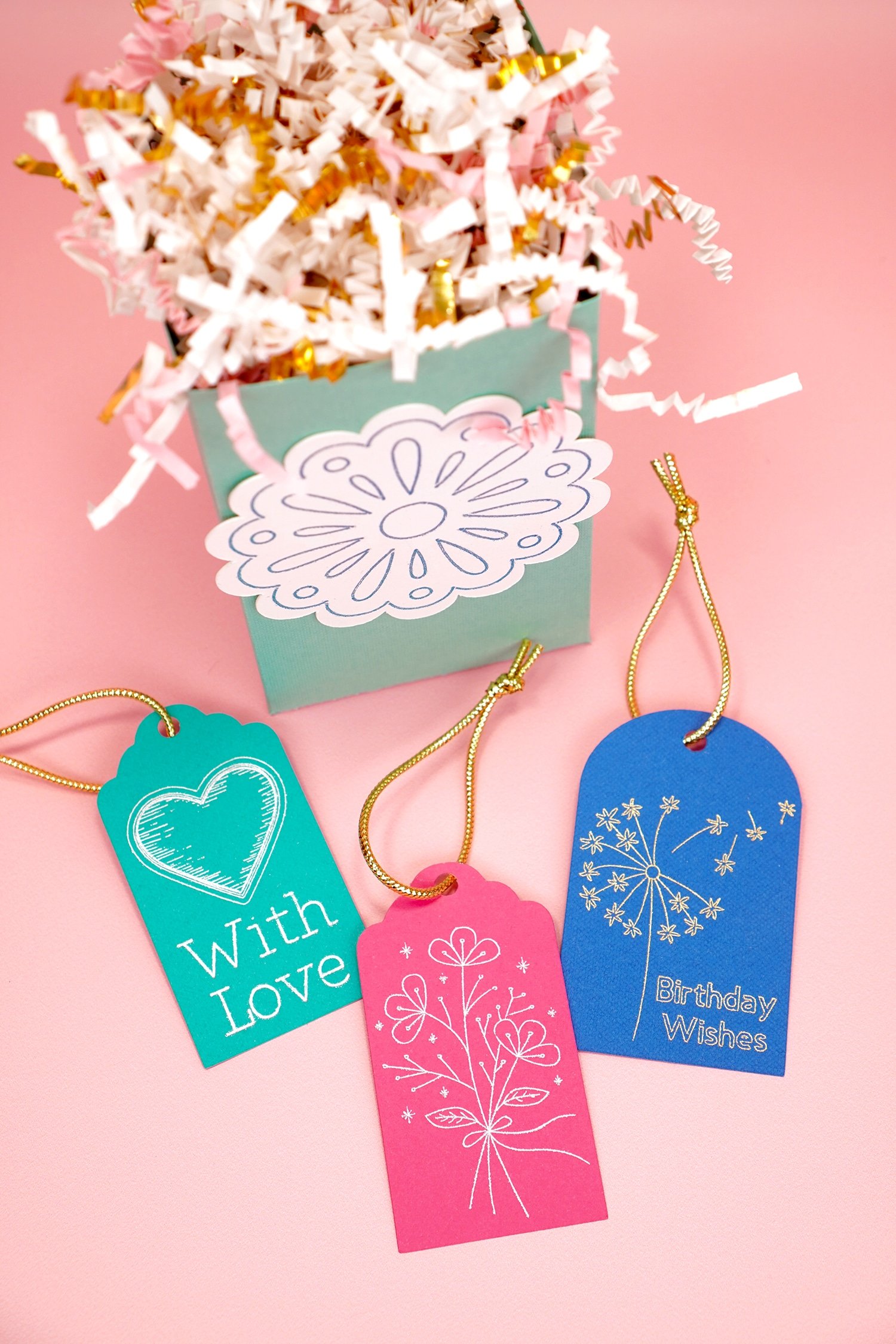 Colorful foil embellished gift tags and gift bag on coral background