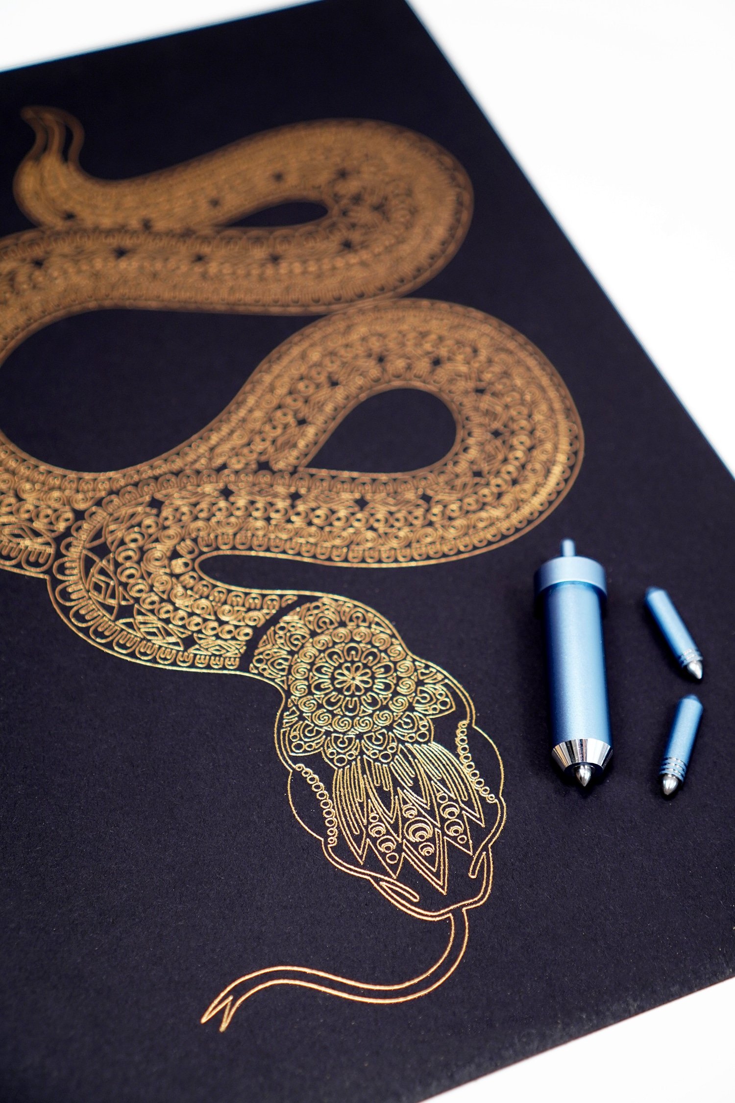 Close up of gold foil art print detail - snake with mandala designs and Cricut Foil Transfer Tool on black