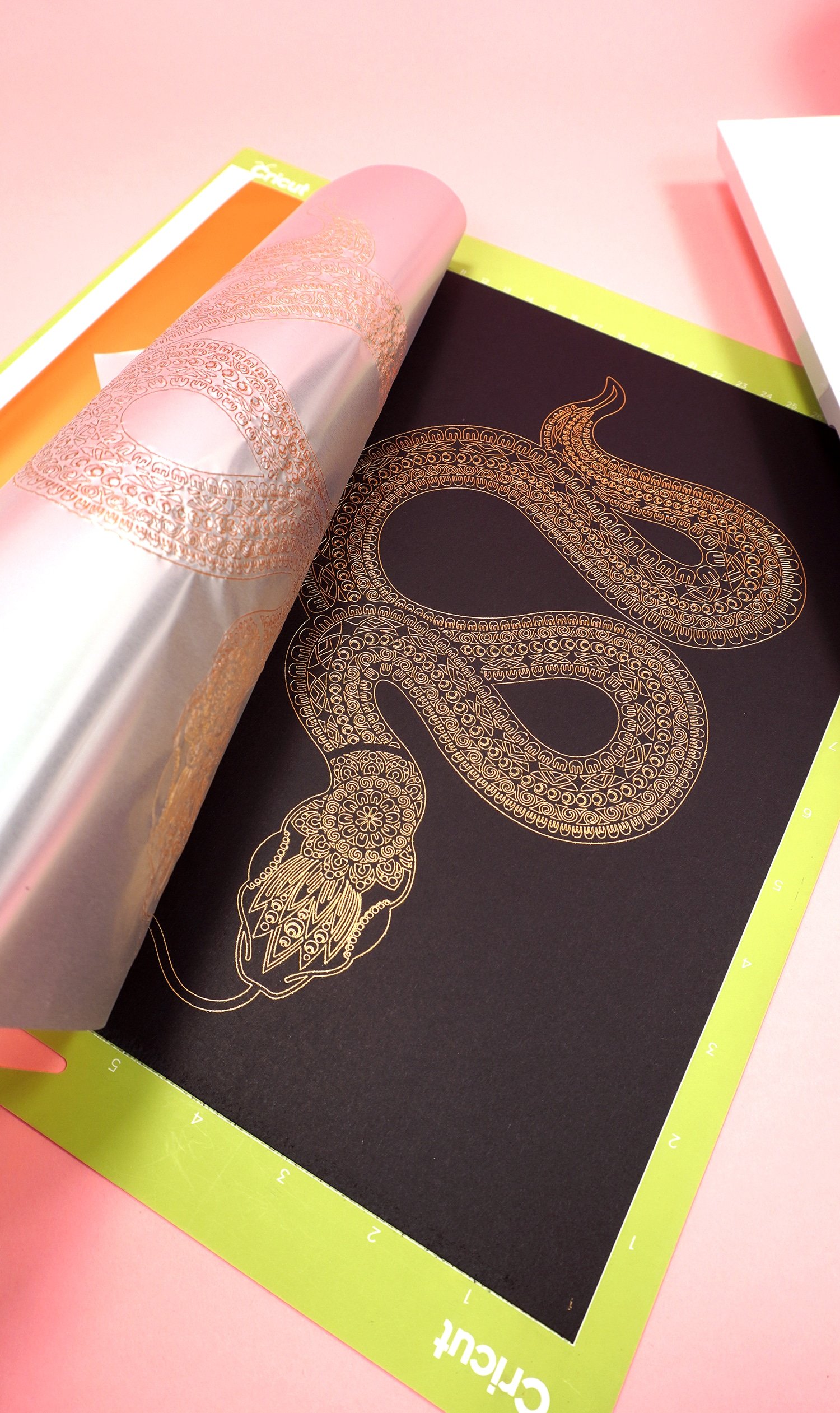 Peeling back gold foil transfer sheet to reveal gold foil art print of a snake