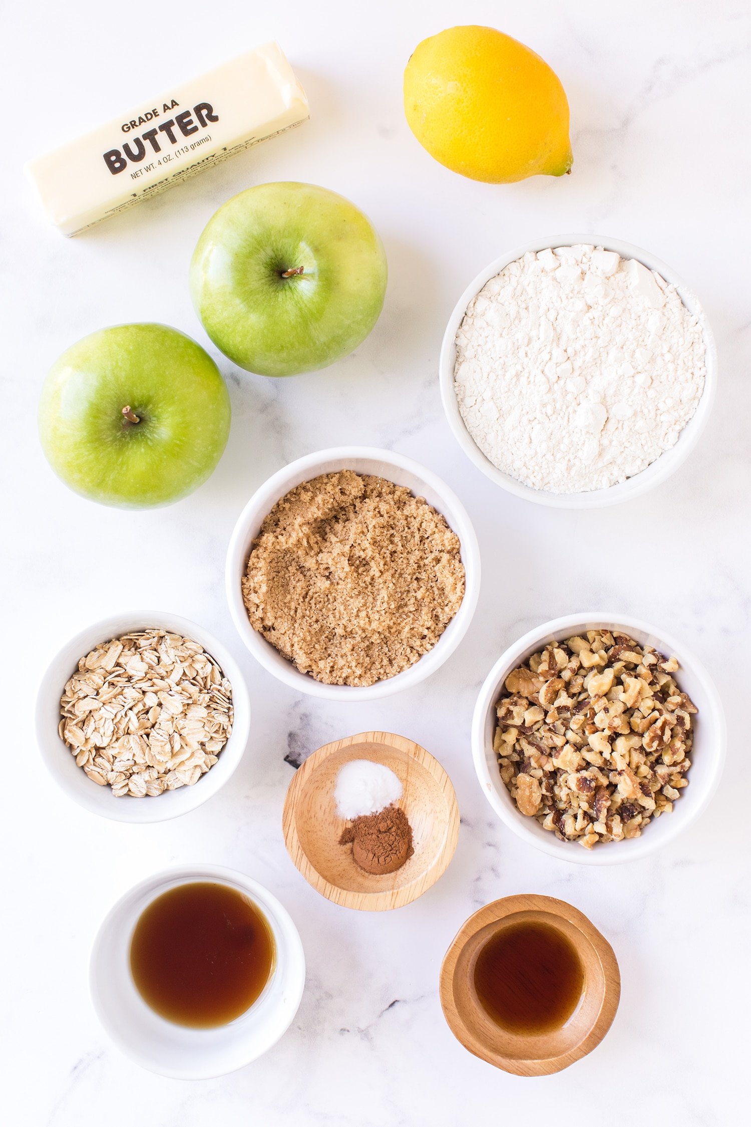 Ingredients for Apple Pie Bars in small bowls on white marble background