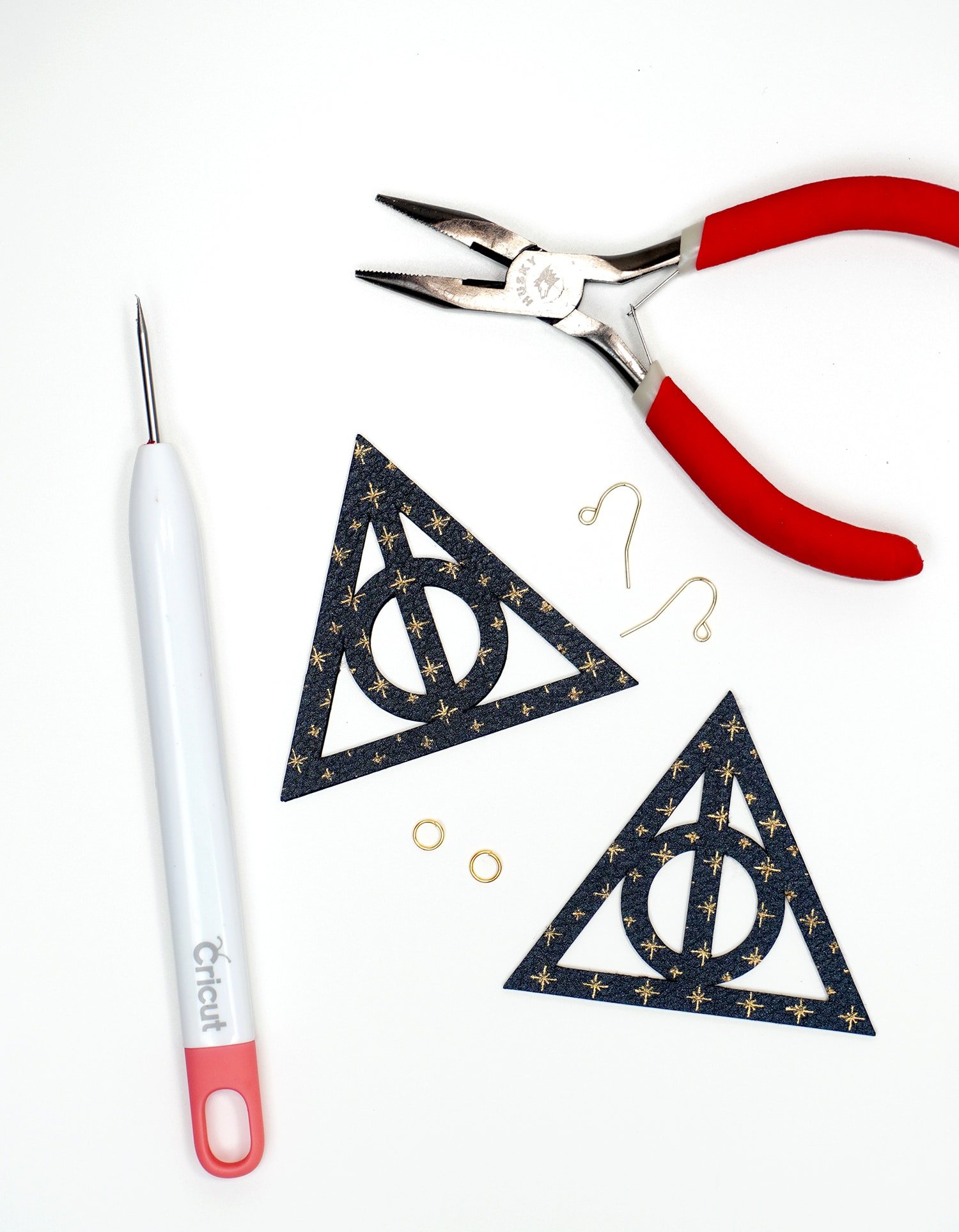 Deathly Hallows shapes on white background surrounded by earring making tools