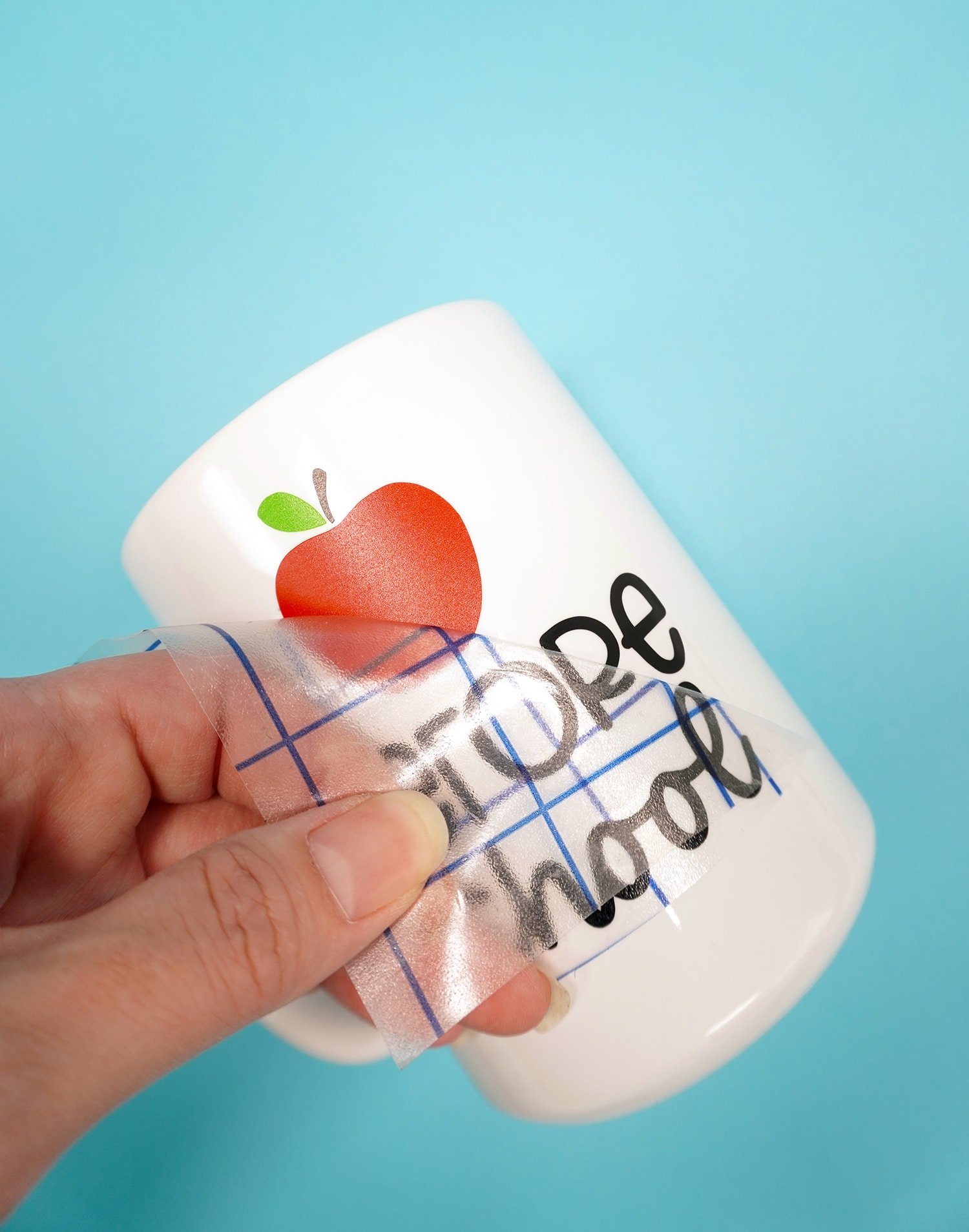 White mug on blue background - peeling transfer tape to reveal apple design