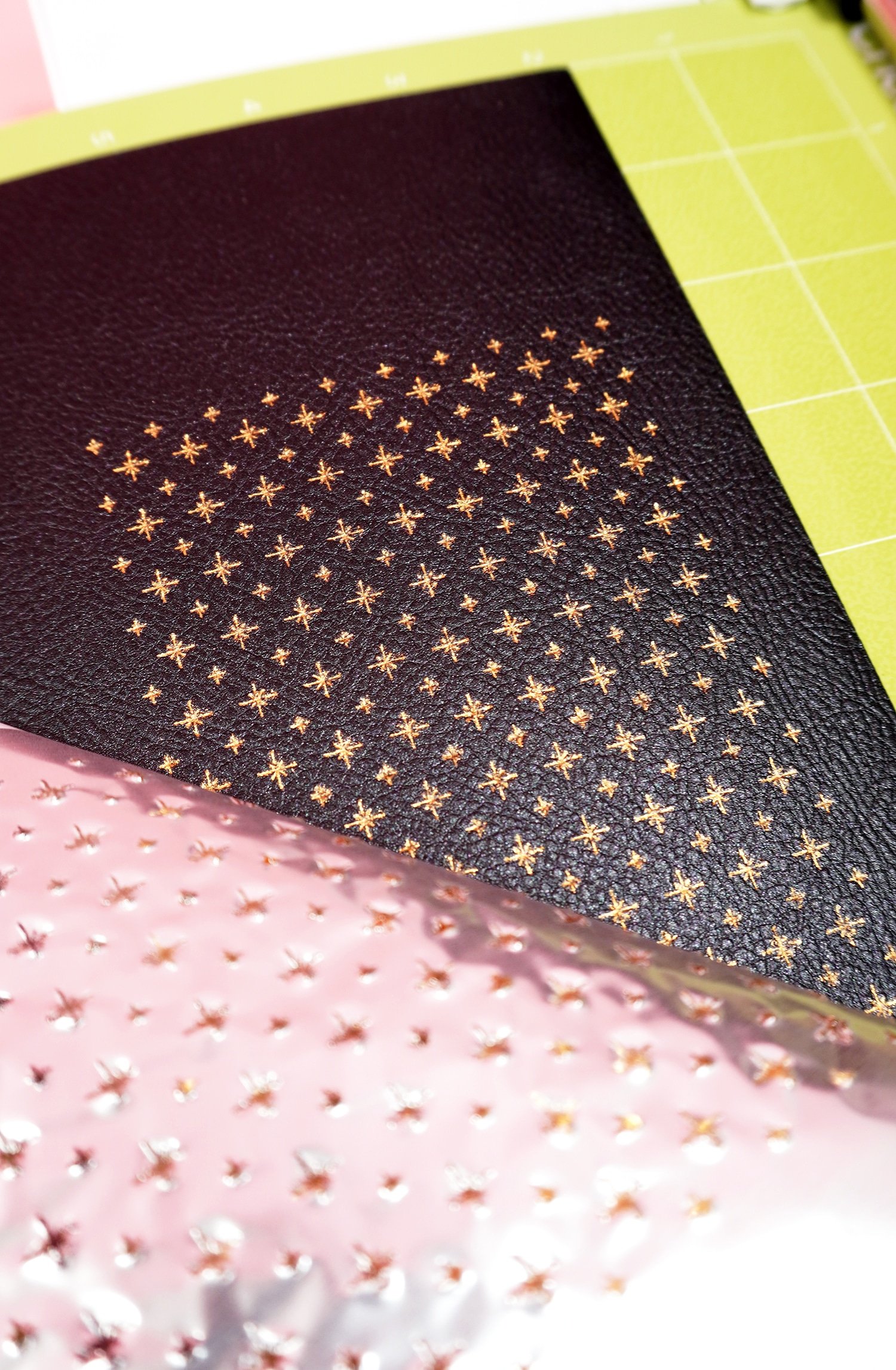 Peeling back gold foil from black faux leather to reveal star design