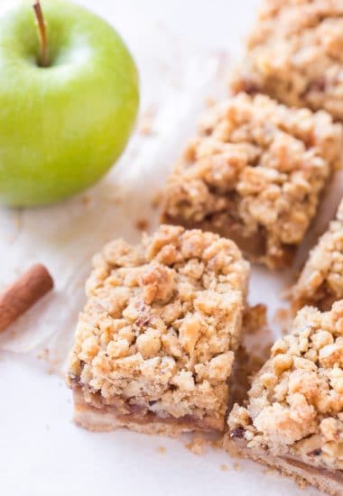 Sliced apple pie bars with green apples and cinnamon sticks in background