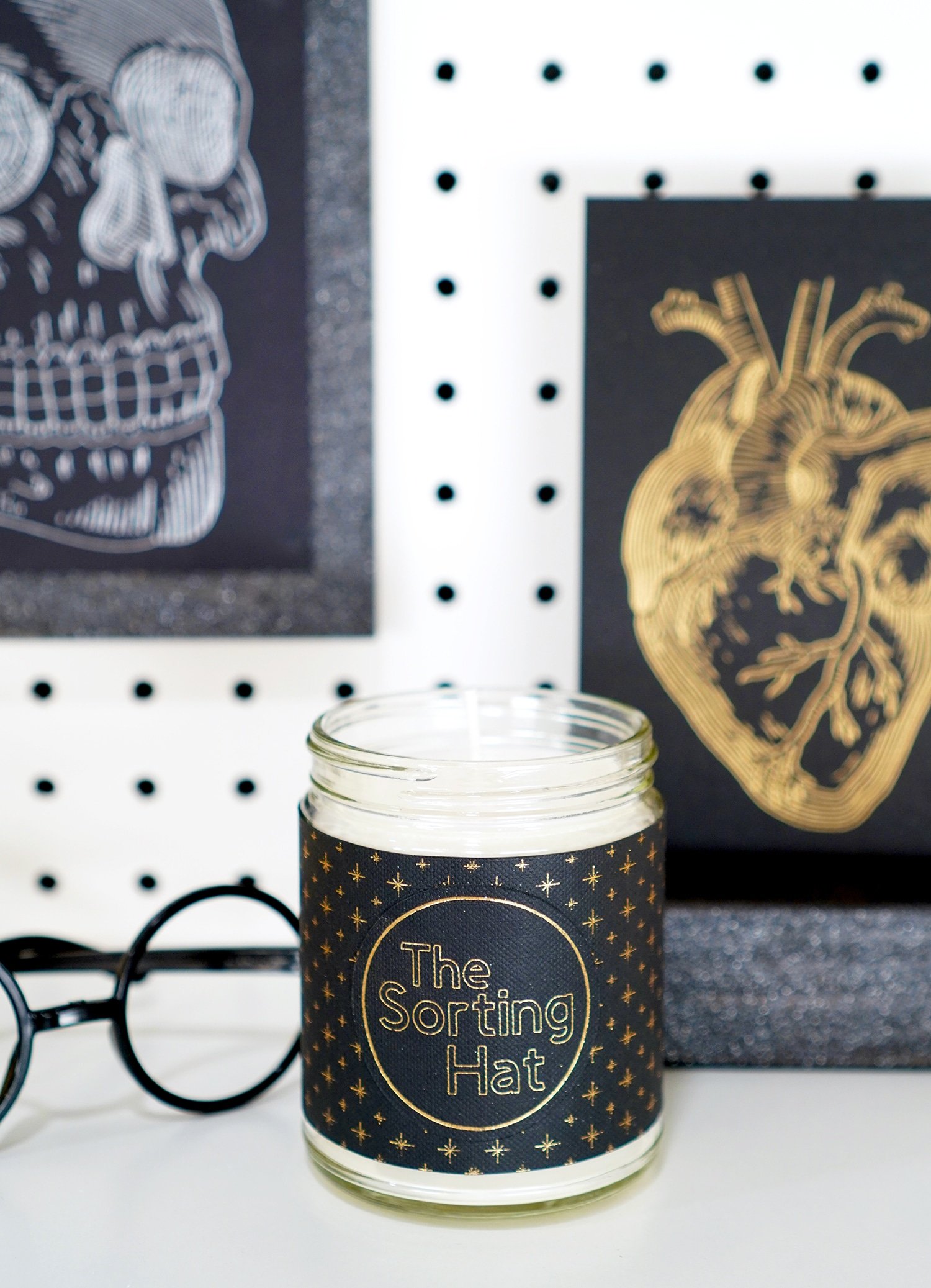 "The Sorting Hat" candle with black label with gold stars with Harry Potter glasses, foil skull and anatomical heart prints in background