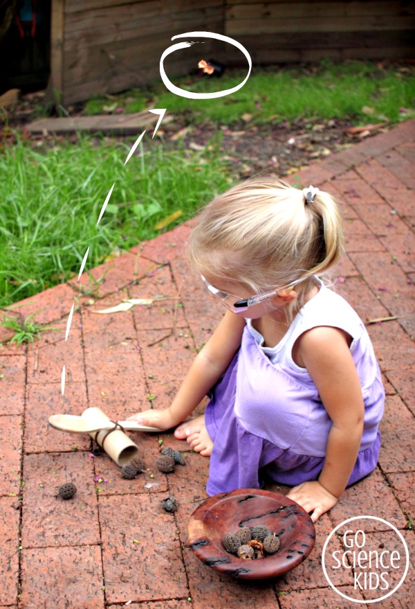 little girl playing with handmade catapults in yard