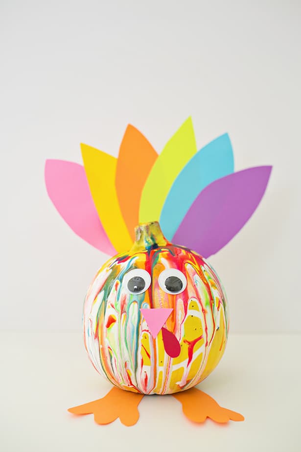 squeeze painted pumpkin with feathers resembled turkey