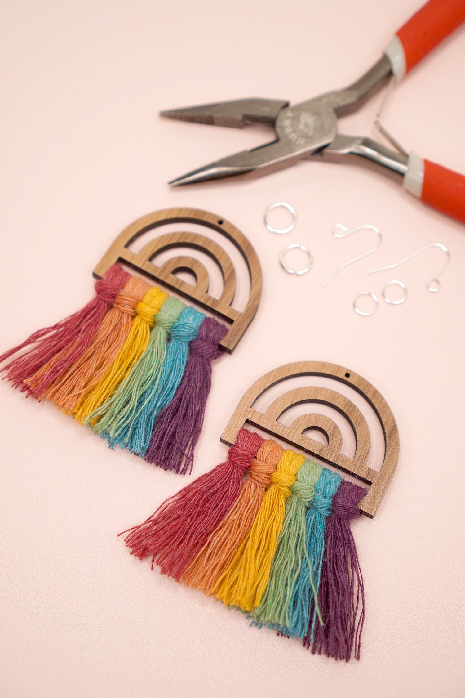 Rainbow macrame frames with earring wires, jump rings, and jewelry pliers in background