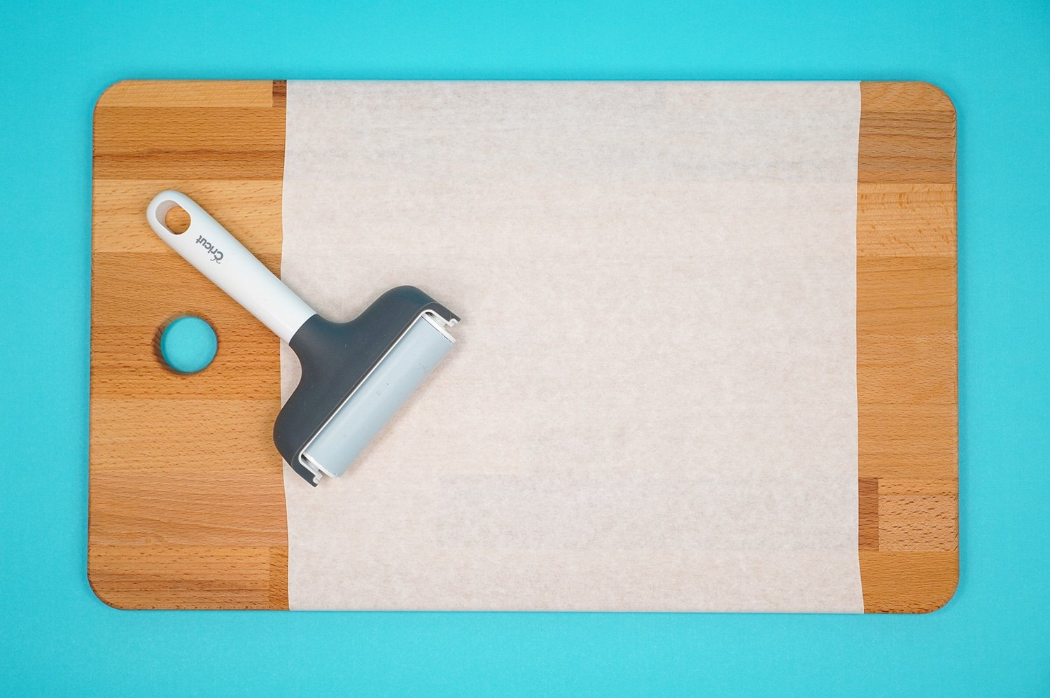 Cutting board with masking and a brayer on aqua background