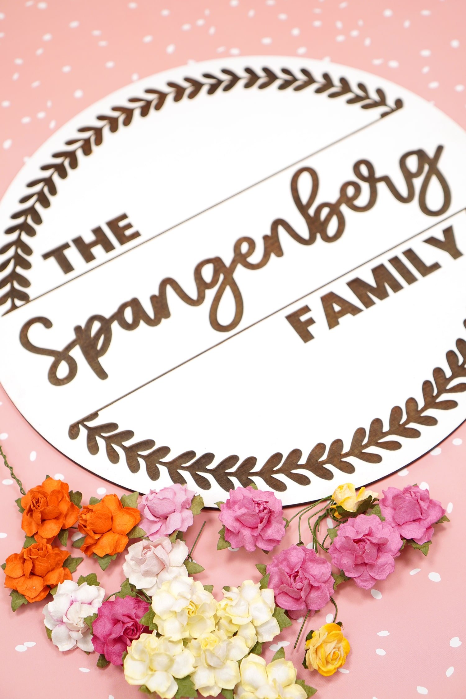 "The Spangenberg Family" white Glowforge engraved round wood sign with flowers on pink dotted background