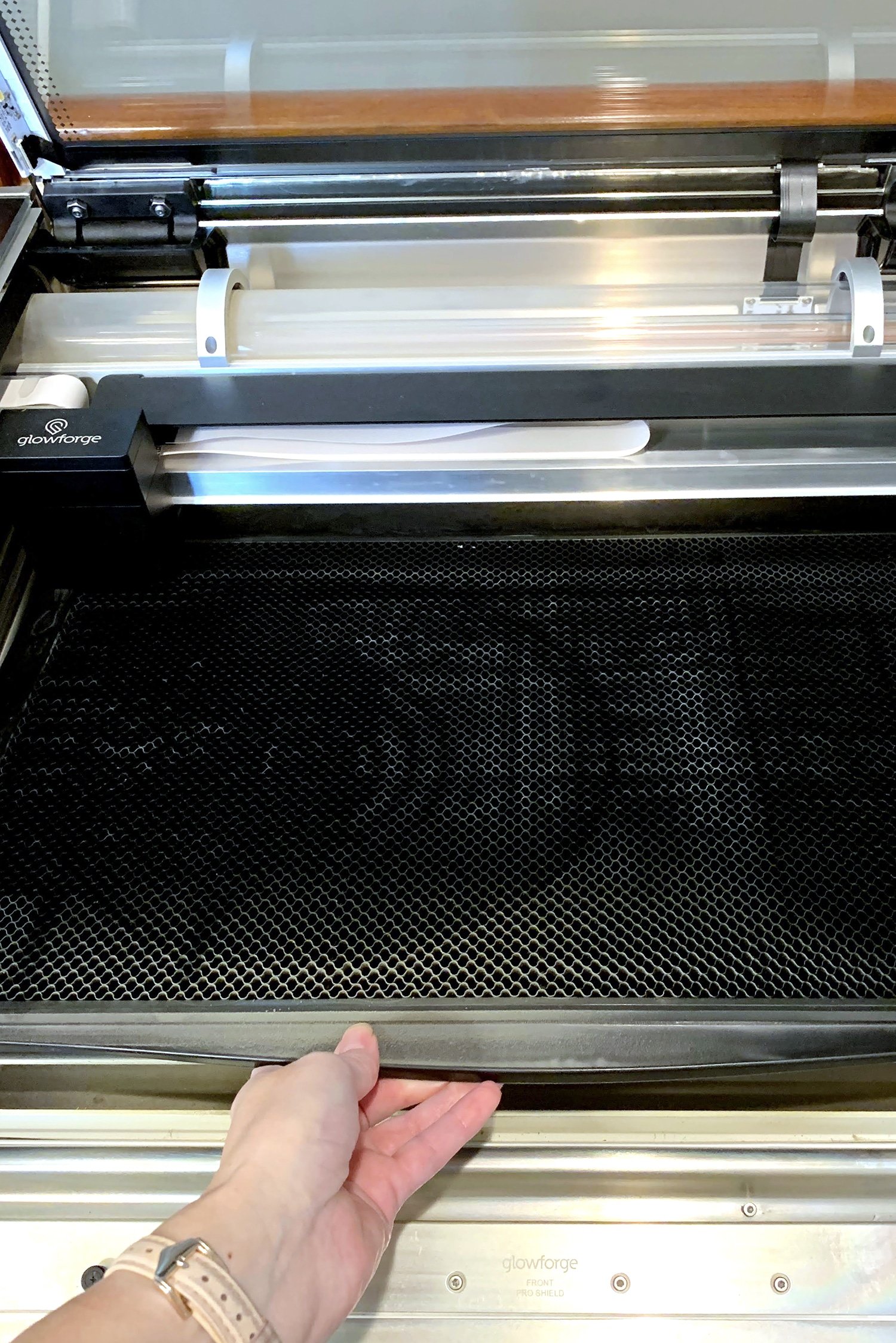 Hand removing the crumb tray from Glowforge machine