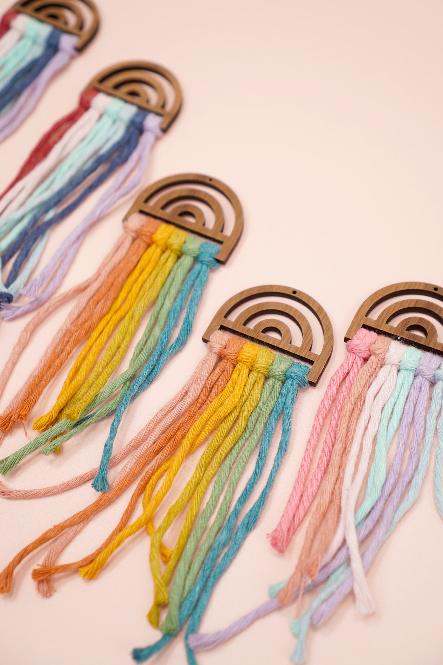 Assorted untrimmed rainbow macramé earrings on peach background