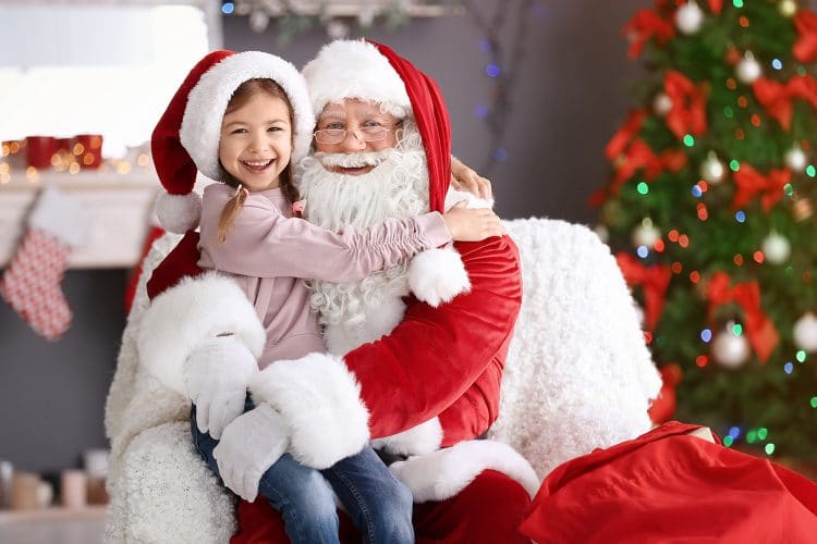 little girl in santa hat sitting on santas lap