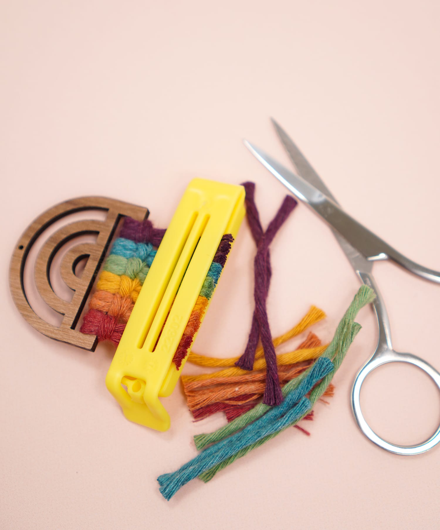 Trimmed Rainbow Macrame Earrings on peach background with scissors and bag clip