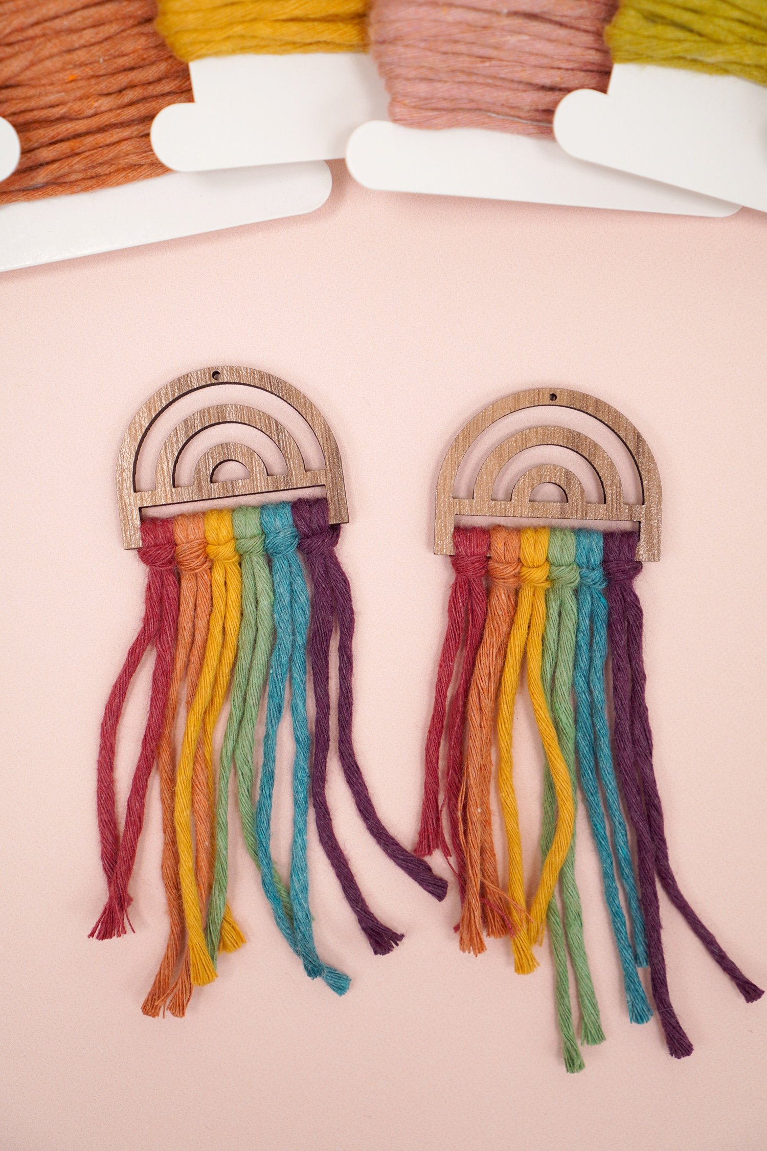Untrimmed Rainbow Macrame Earrings on peach background with macrame cord