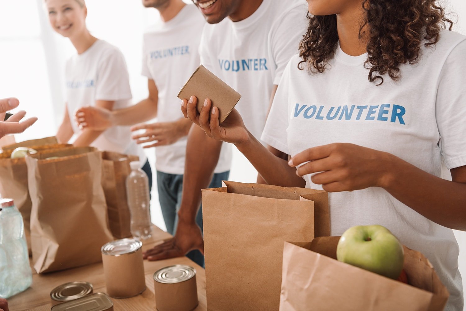 volunteers packing brown paper bags in a line