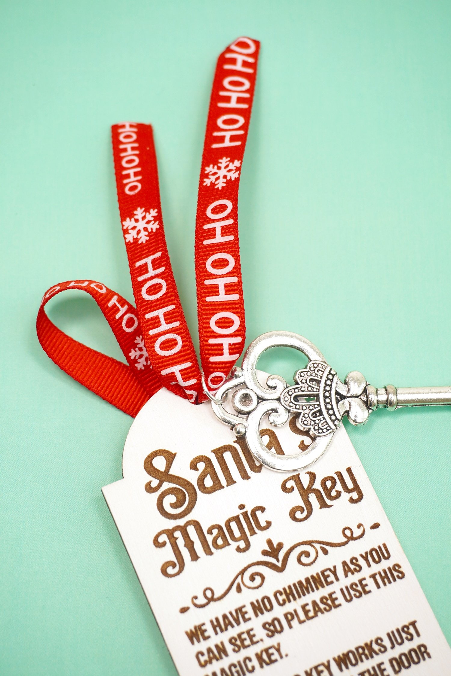Adding a red ribbon and silver key to a laser engraved Santa's Magic Key tag