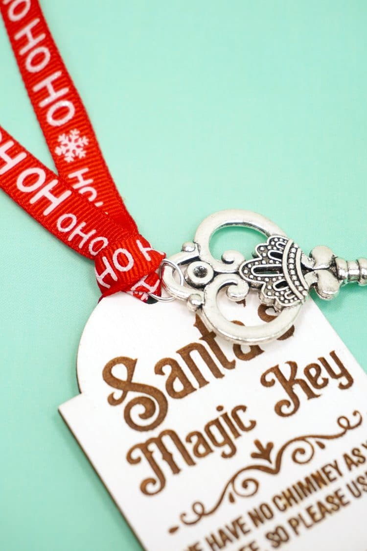 Close up of red ribbon and silver key tied to a laser engraved Santa's Magic Key tag
