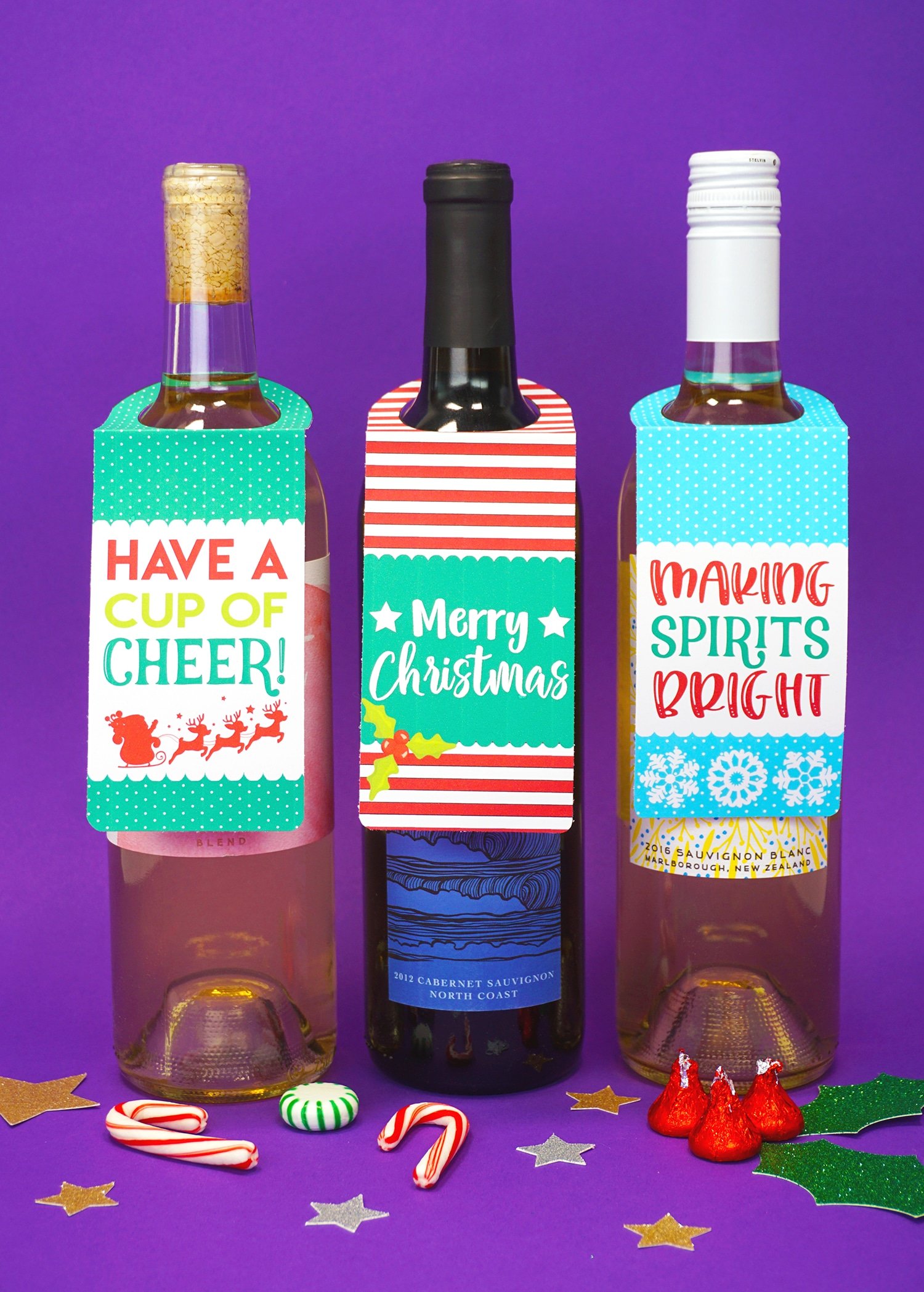 Three bottles of wine on purple background with "Have a Cup of Cheer" and "Merry Christmas" and "Making Spirits Bright" printable Christmas wine bottle gift tags