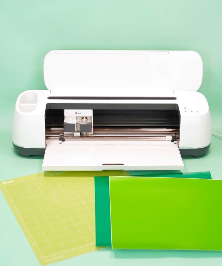 Cricut Maker machine with two shades of green vinyl and mat on mint green background