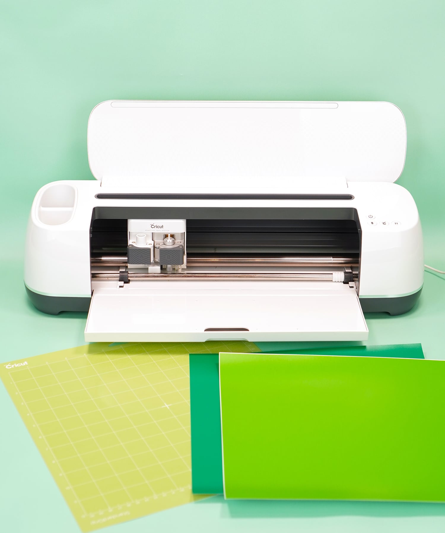 Cricut Maker machine with two shades of green vinyl and mat on mint green background