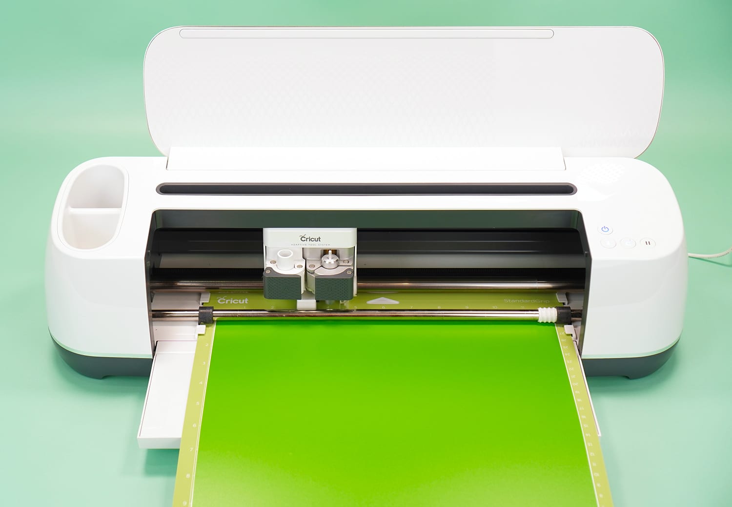 Cricut Maker machine with lime green vinyl on mat on mint green background