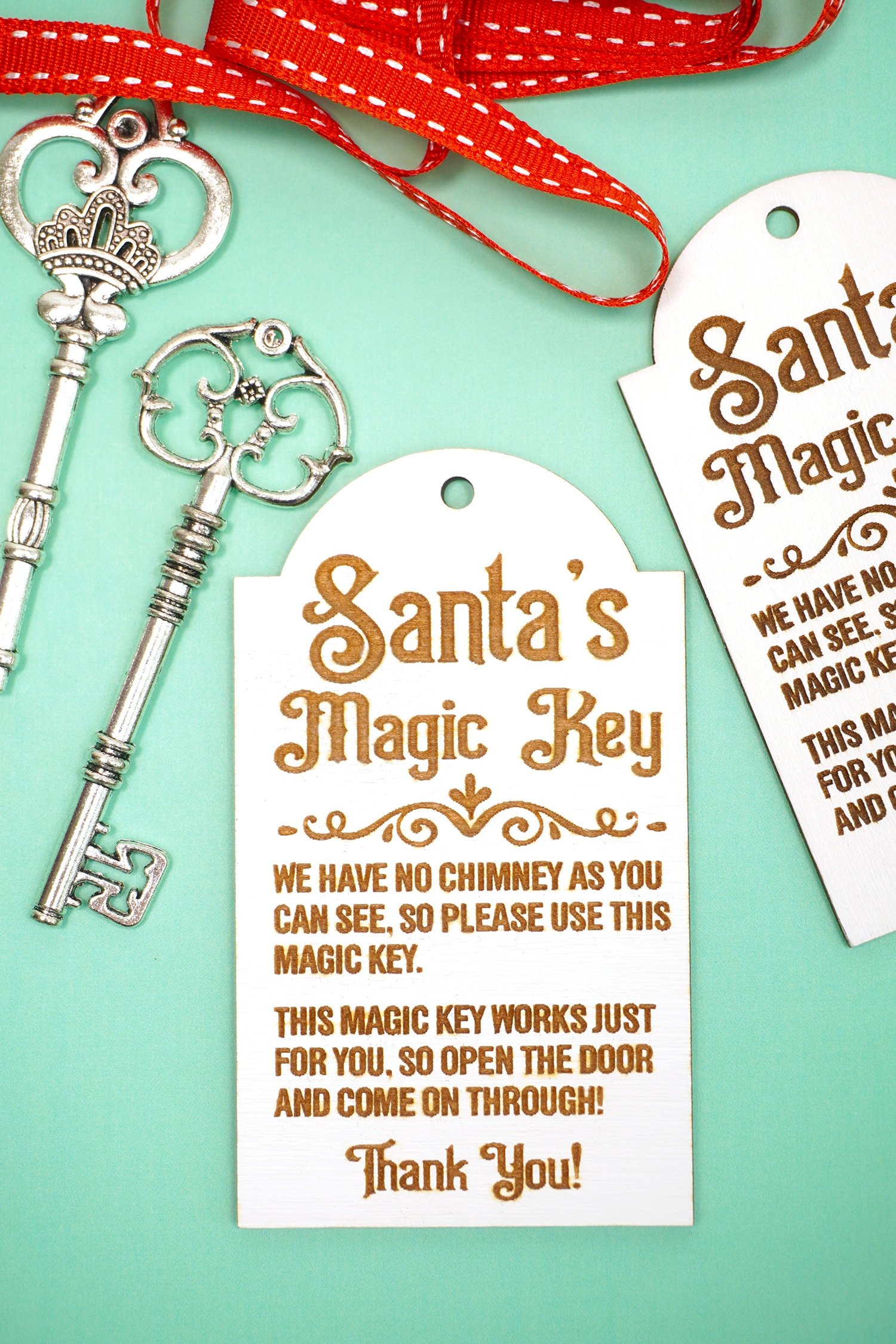 Laser engraved Santa's Magic Key wood tags with red ribbon and silver keys on a mint green background