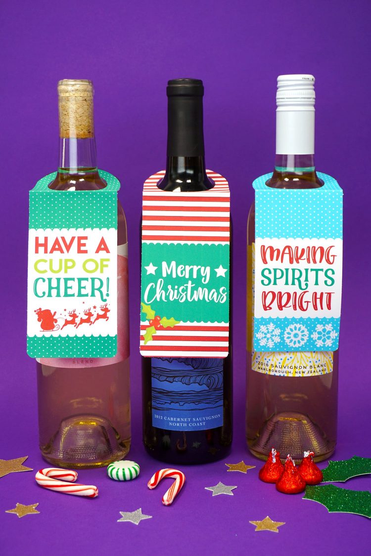 Three bottles of wine on purple background with "Have a Cup of Cheer" and "Merry Christmas" and "Making Spirits Bright" printable Christmas wine bottle gift tags