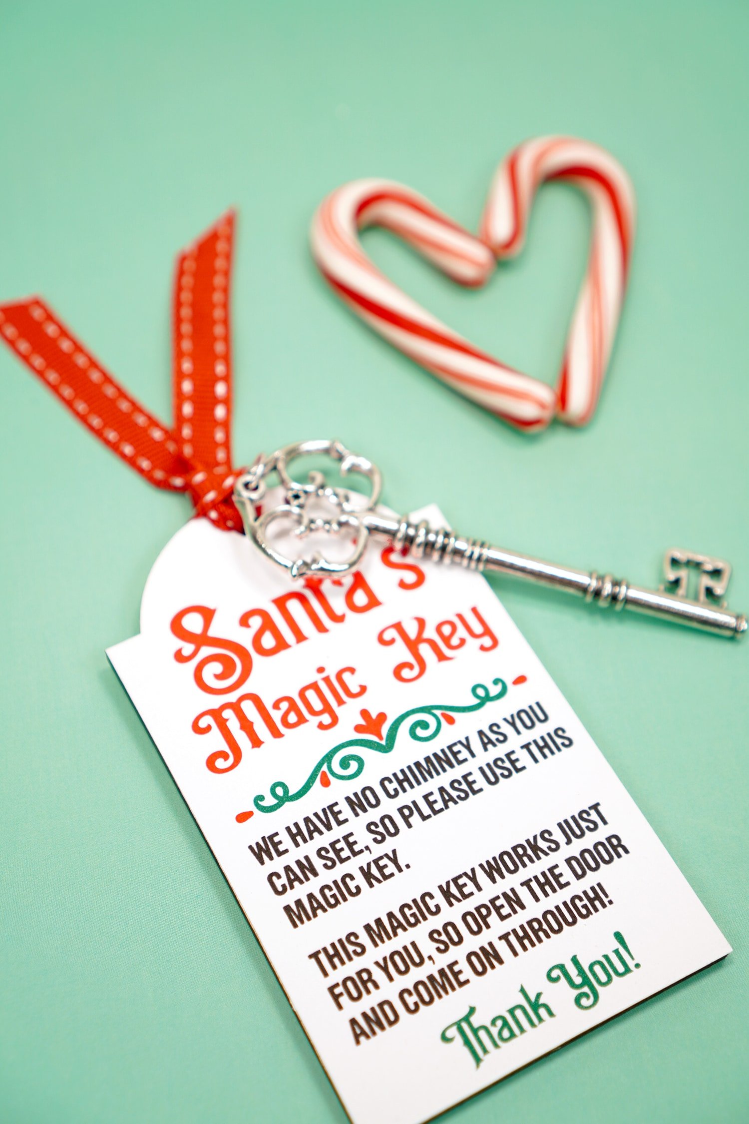 Santa's Magic Key printable tag with red ribbon and silver key on a mint green background with candy canes