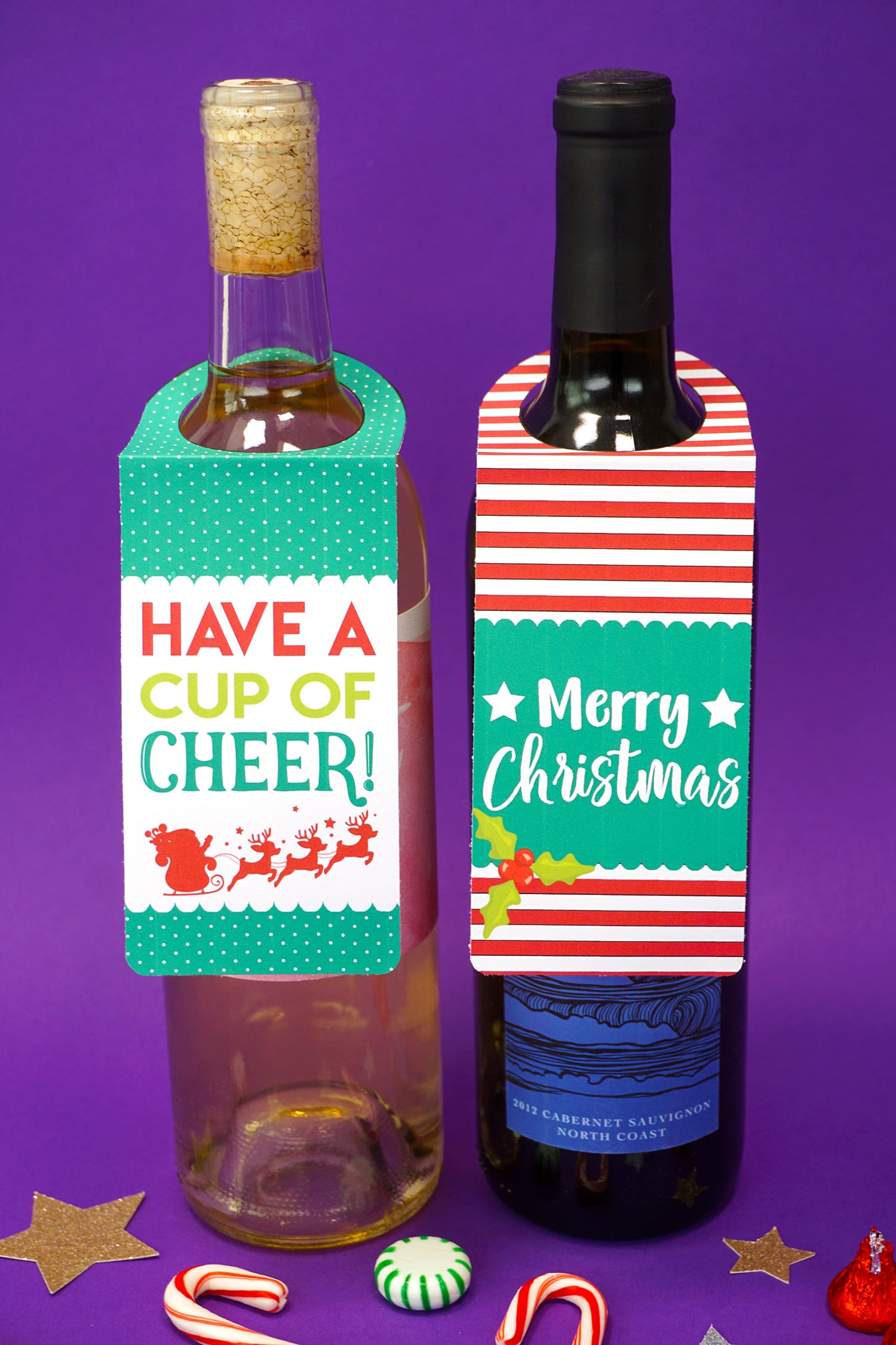 Two bottles of wine on purple background with "Have a Cup of Cheer" and "Merry Christmas" printable Christmas wine bottle gift tags