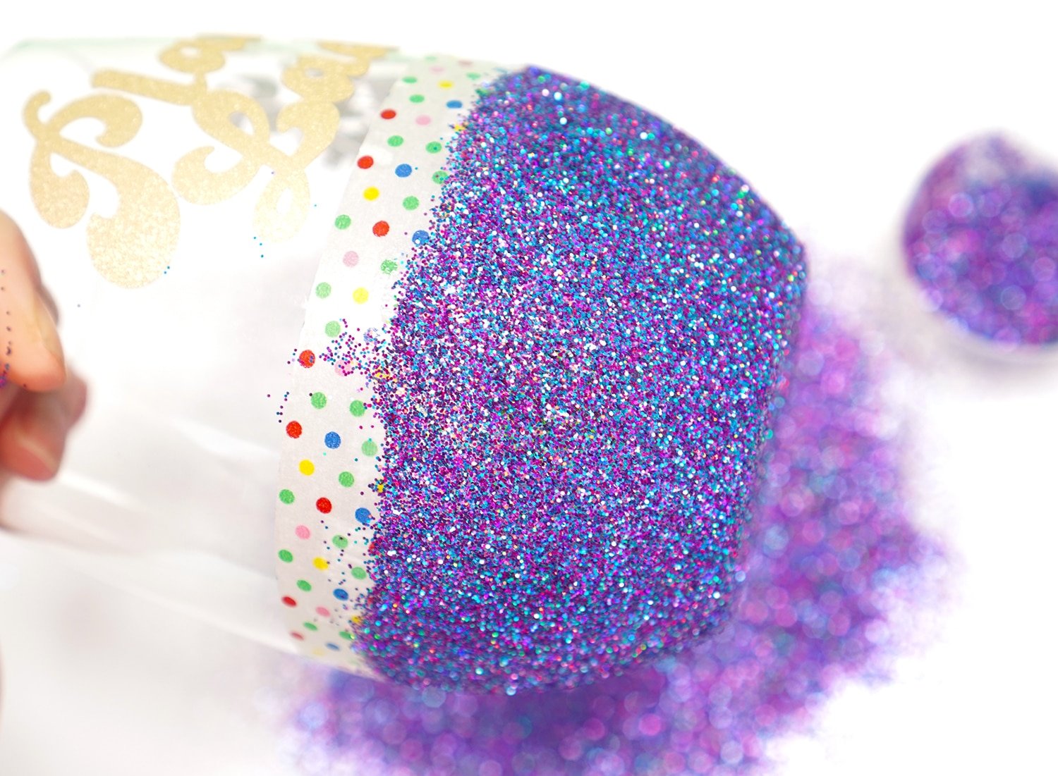 Close up of applying multi-hued purple glitter to the bottom of a stemless wine glass