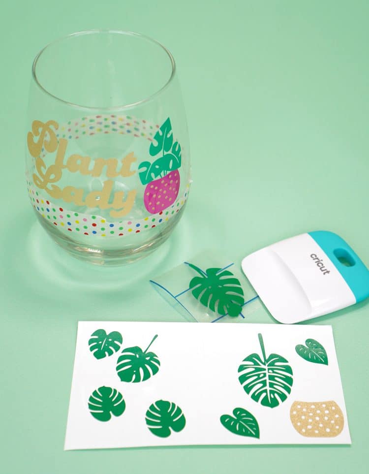 "Plant Lady" decals on wine glass with sheet of vinyl leaf decals in foreground