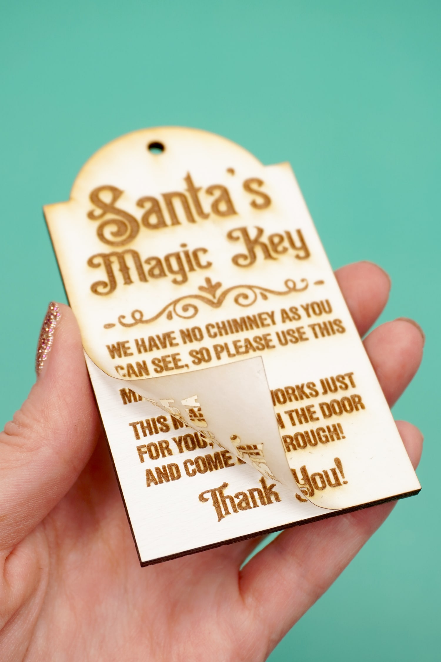 Peeling the masking from a laser engraved Santa's Magic Key wood tag